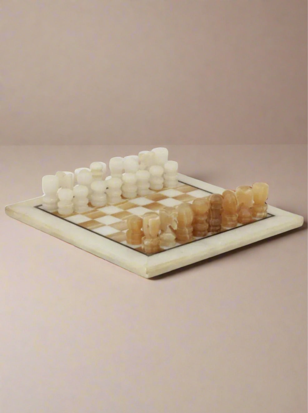 A vintage chessboard, the Vintage Marble Chessboard by Boga Avante Shop, features a marble stone board with alternating square patterns and hand-carved pieces made from marble. The pieces are in two colors, with creamy white pieces on one side and light brown pieces on the other, all arranged for the start of the game.