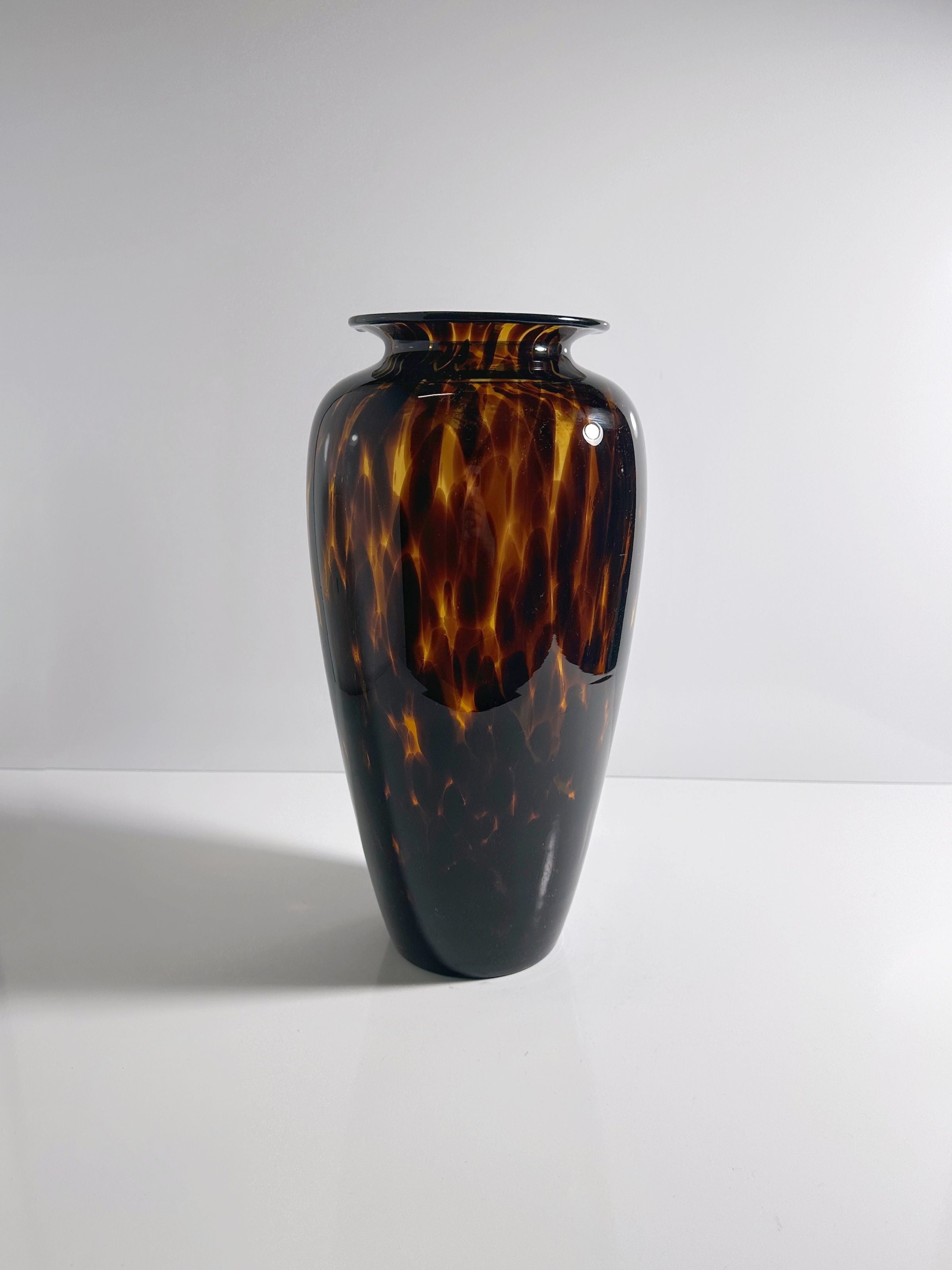 The Tall Murano Tortoise Vase by Dodo Vintage stands against a white background, showcasing its rich brown and amber tones through the Tortoise speckle technique on a smooth, reflective surface.