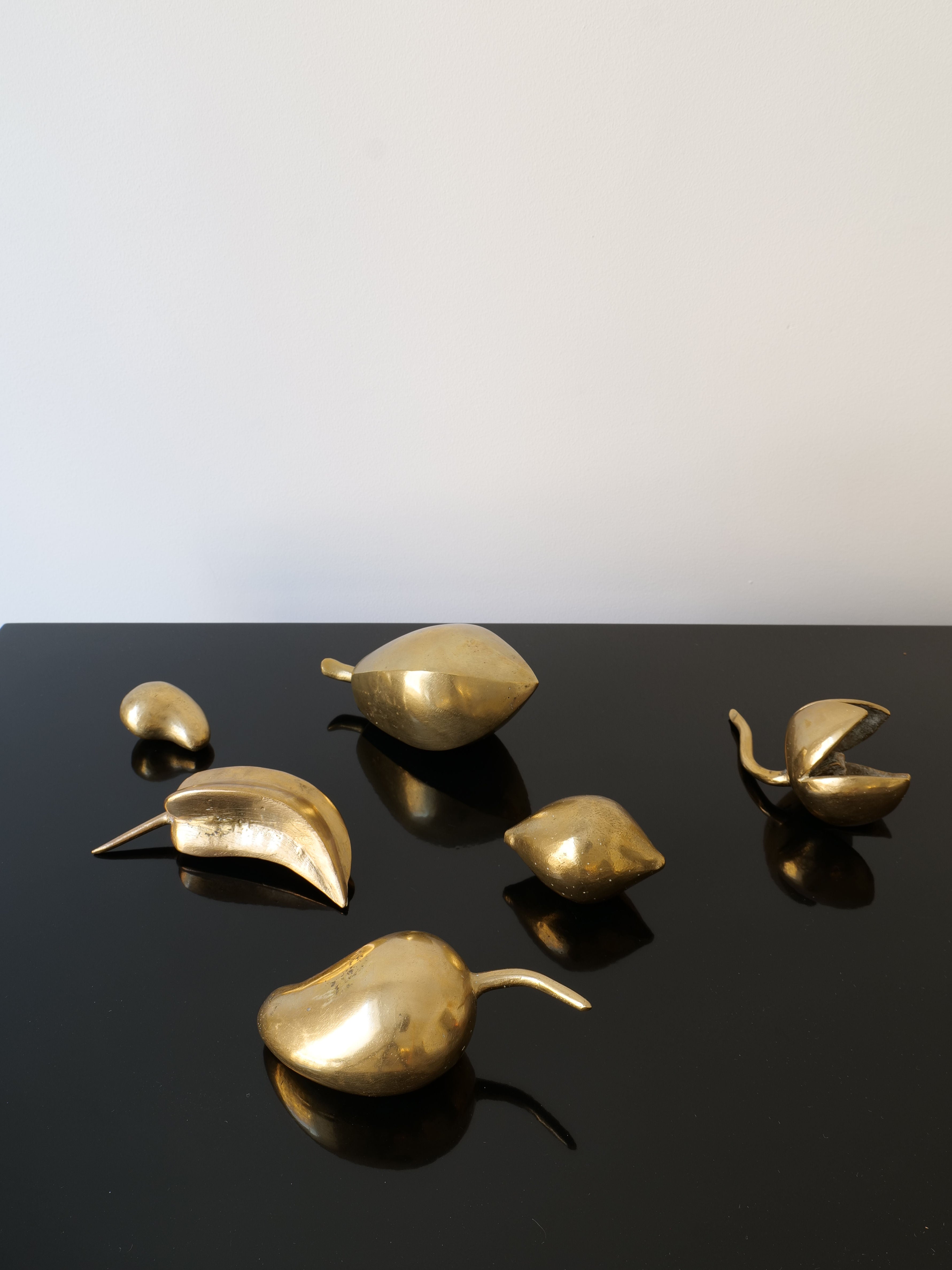 The Brass Sculpture Collection by Collection apart features elegantly arranged solid brass sculptures in golden, abstract shapes resembling leaves and fruits, set against a glossy black surface and a plain light-colored background, evoking a French midcentury aesthetic.