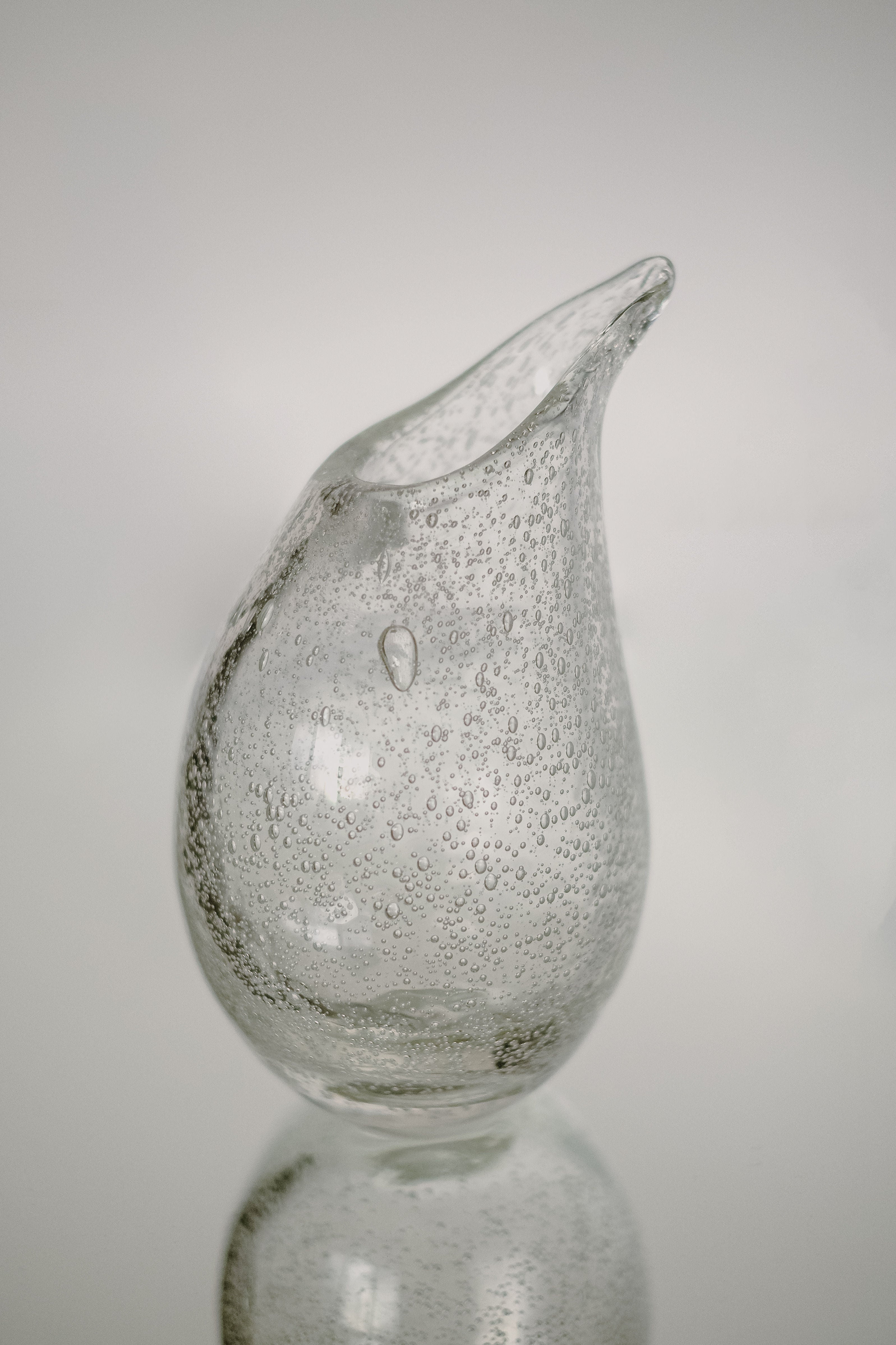 The Small Bubble Vase by septembre studios showcases exquisite craftsmanship, featuring a uniquely shaped handmade design with a narrow opening and textured surface filled with small bubbles, set against a neutral background.