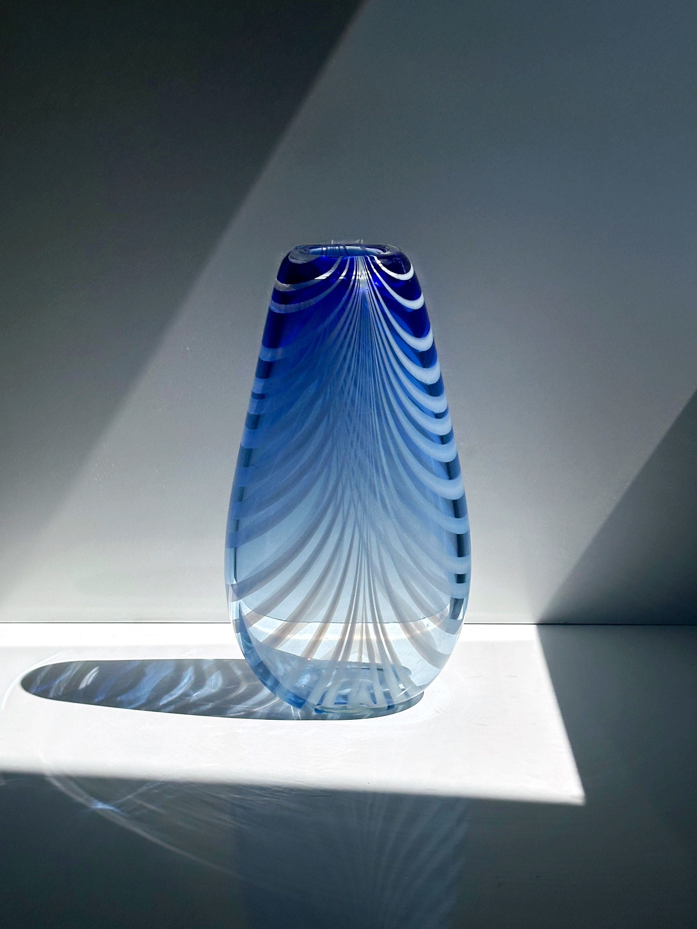 Blue art glass vase with swirled white striped pattern