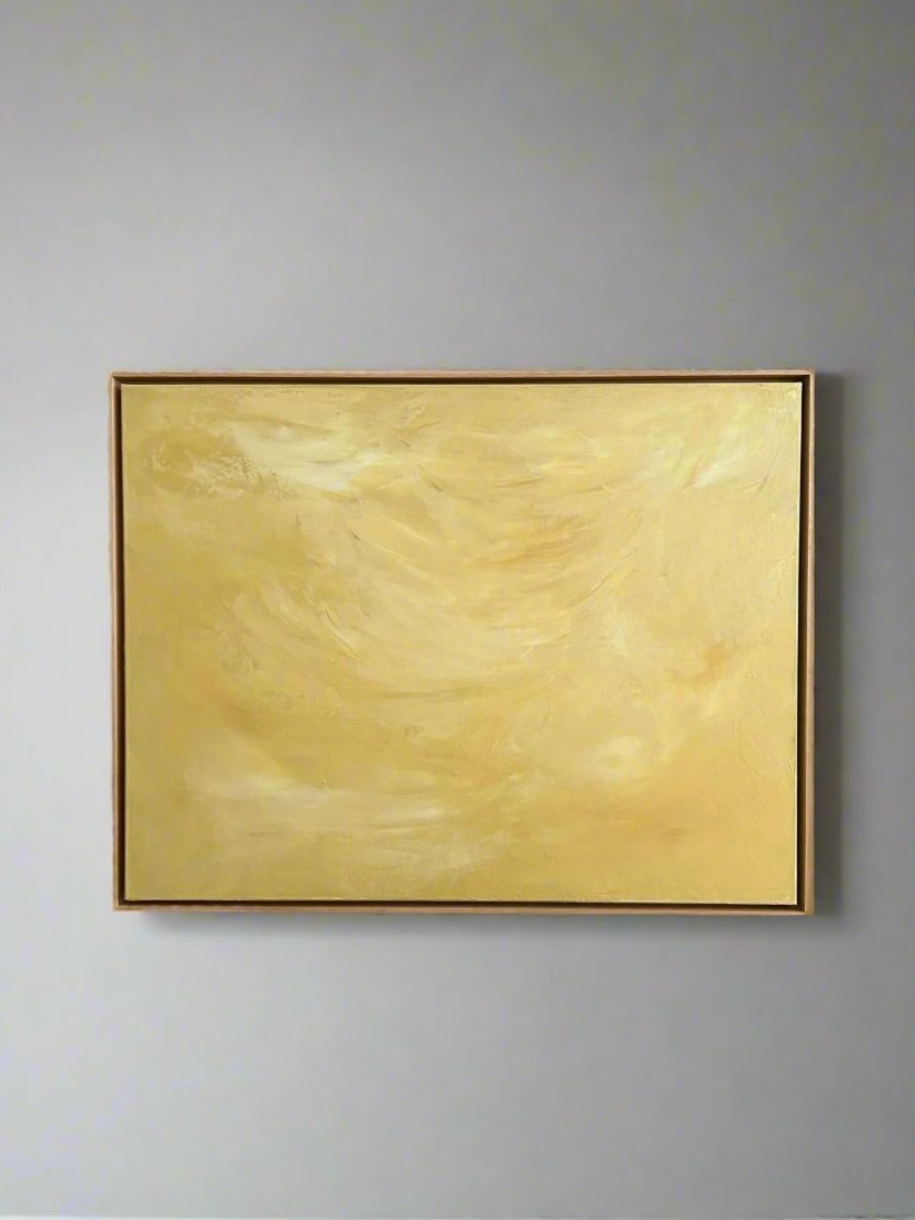 The "Ethereal Light" painting by Mattias Storm, featuring soft swirling shades of yellow and cream in an oak frame, emits an ethereal light when hung on a neutral gray wall.