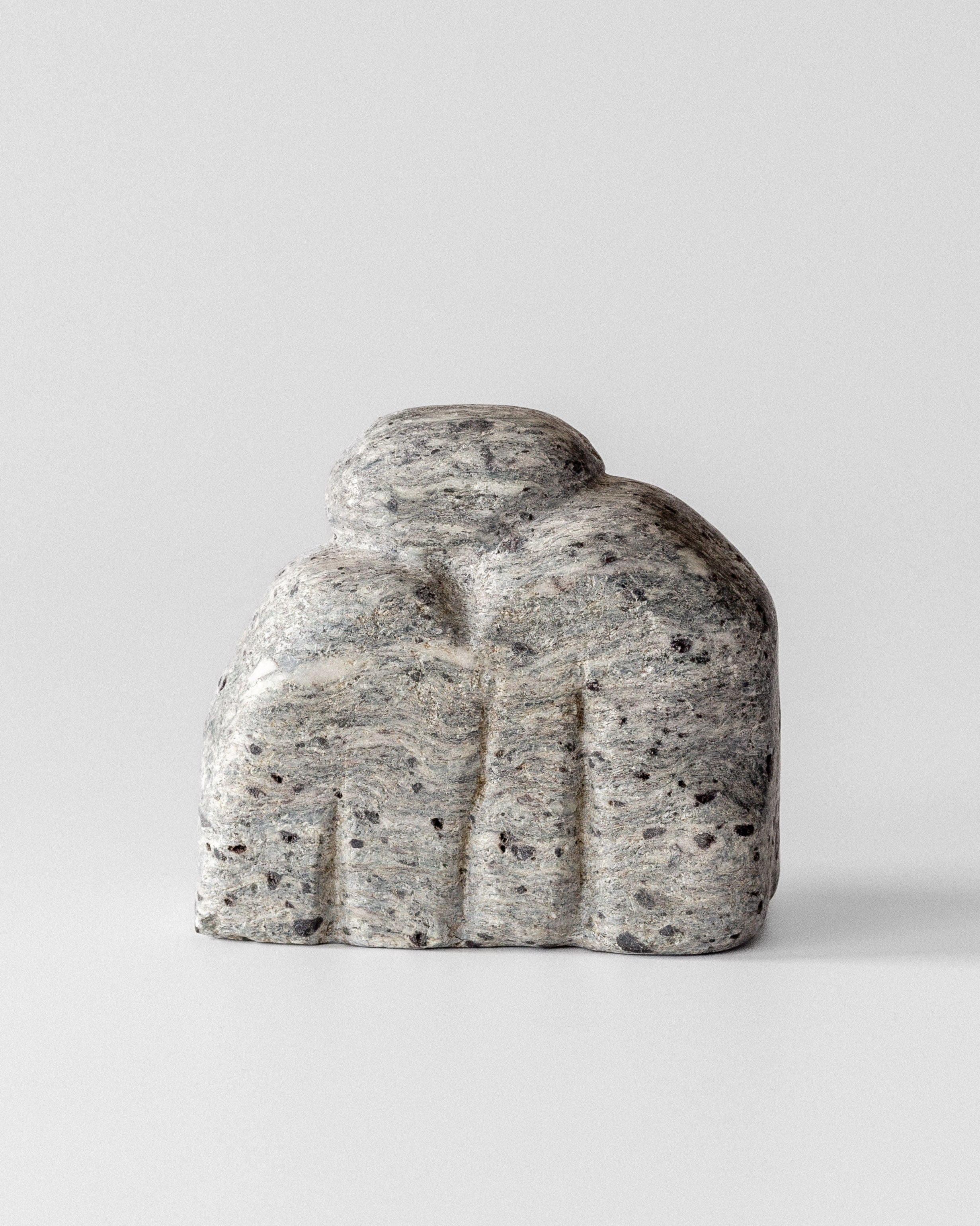Abstract sculptural stone form with curved organic shapes in speckled gray granite