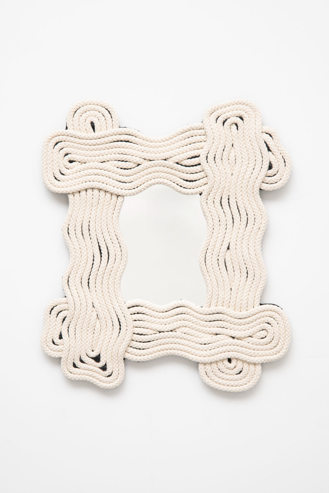 The Frame Mirror Thick by Wendy Andreu features a distinctive rectangular design highlighted by a wavy off-white rope frame, creating an artistic and textured border that stands out against any plain background. Exquisitely handmade, this mirror beautifully captures the charm of Parisian craftsmanship.