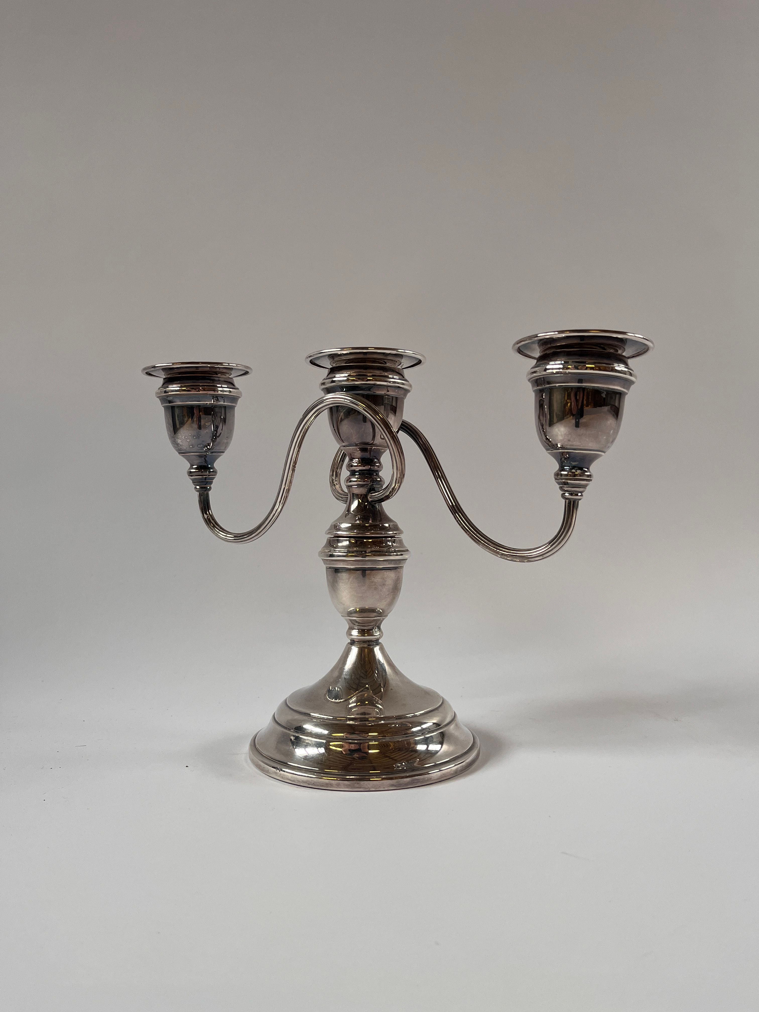 The Maud Vaughan Vintage Silver Plate Candelabra features intricate detailing with three elegantly curved arms and a rounded base, set against a plain gray background.