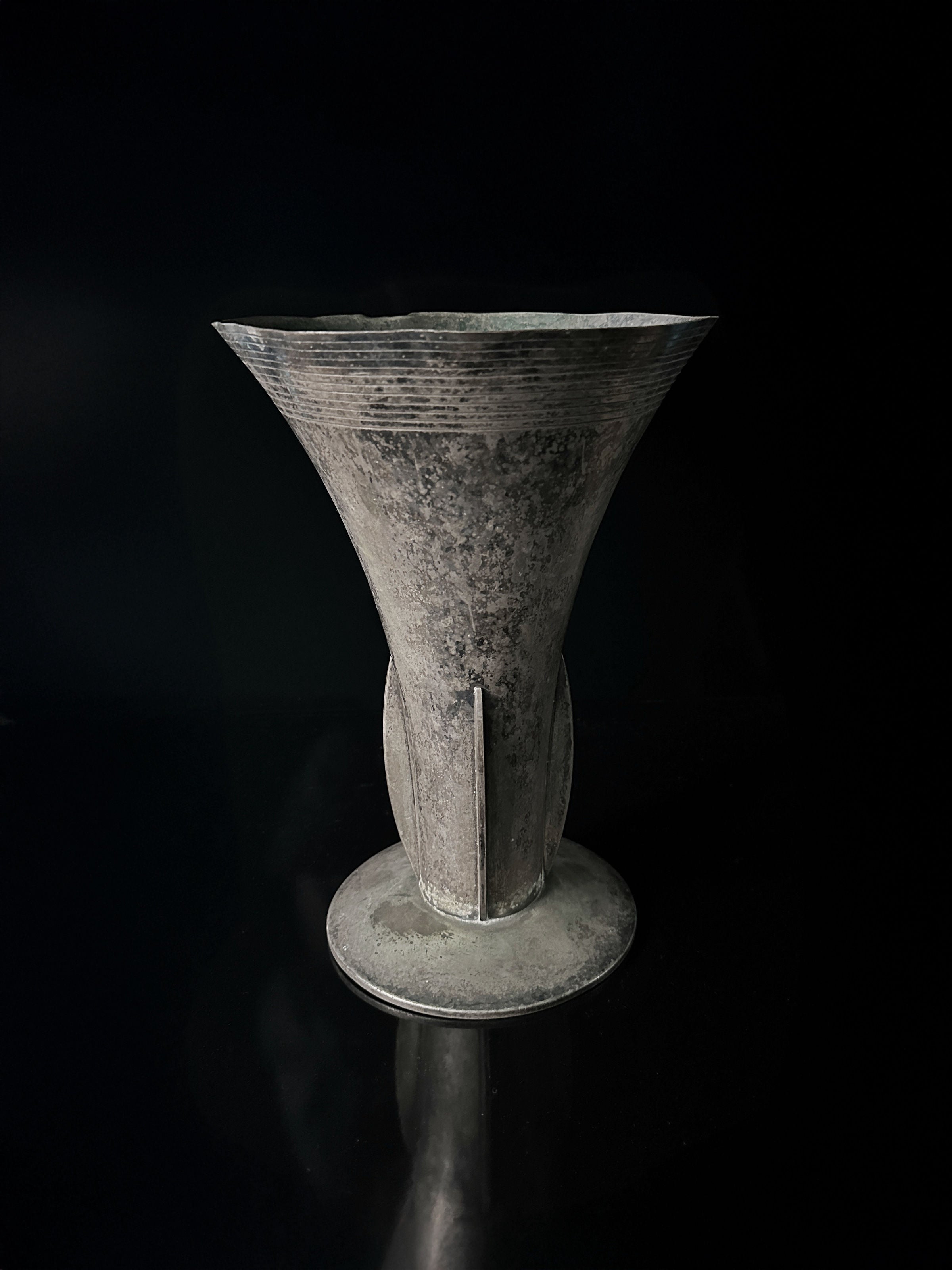 Against a dark background, the large silver-plated amphora vase—WMF 1925 by Dodo Vintage—exhibits its ancient allure, flared funnel shape with vertical and horizontal texture lines, all resting gracefully on a round base while maintaining its original patina.