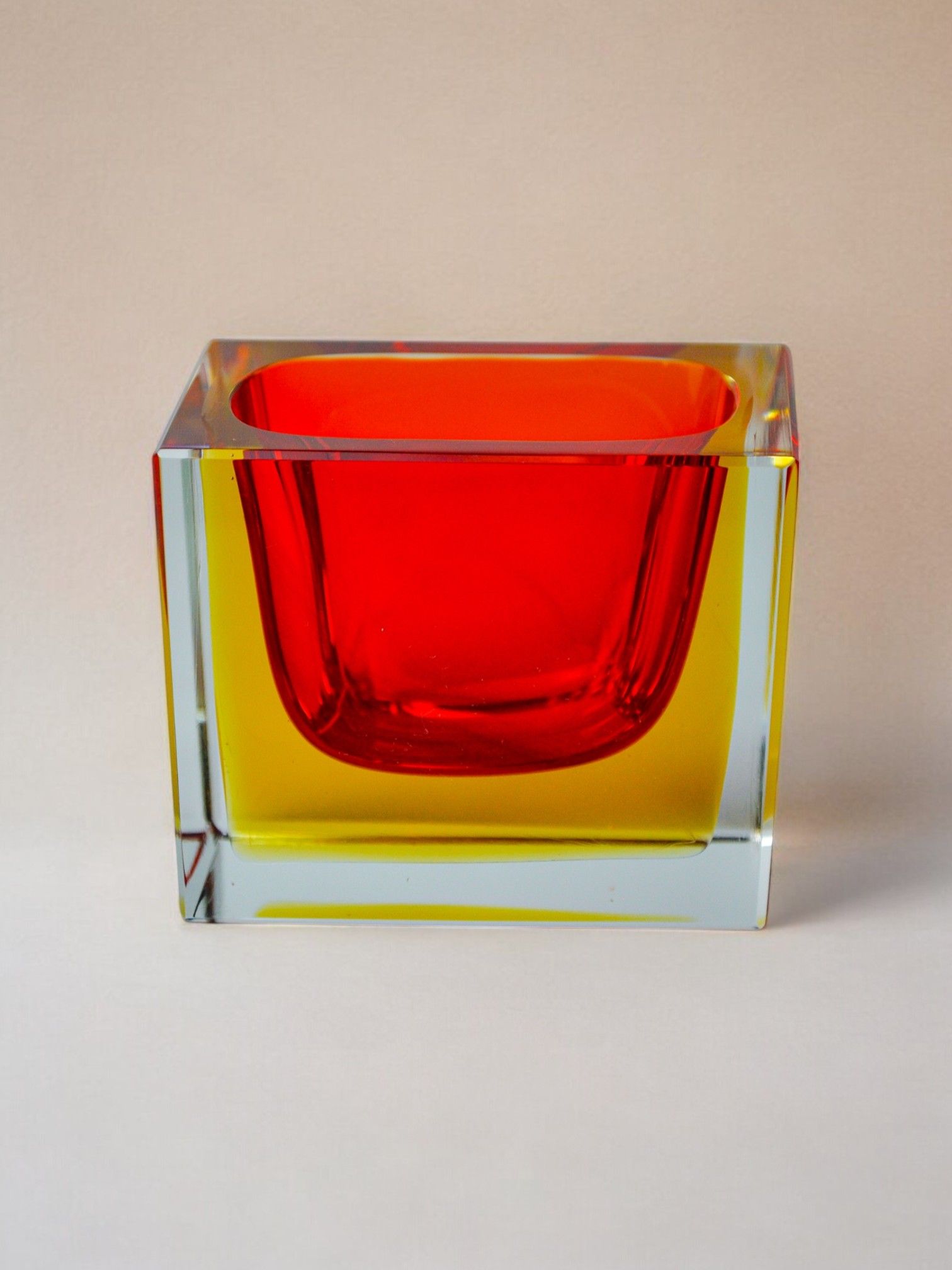 The Sommerso Ashtray by Seguso, Murano 1970 from Malamar Studio, features a gradient of vibrant red and yellow hues with a reflective surface, resembling a rectangular glass vase set against a neutral background.