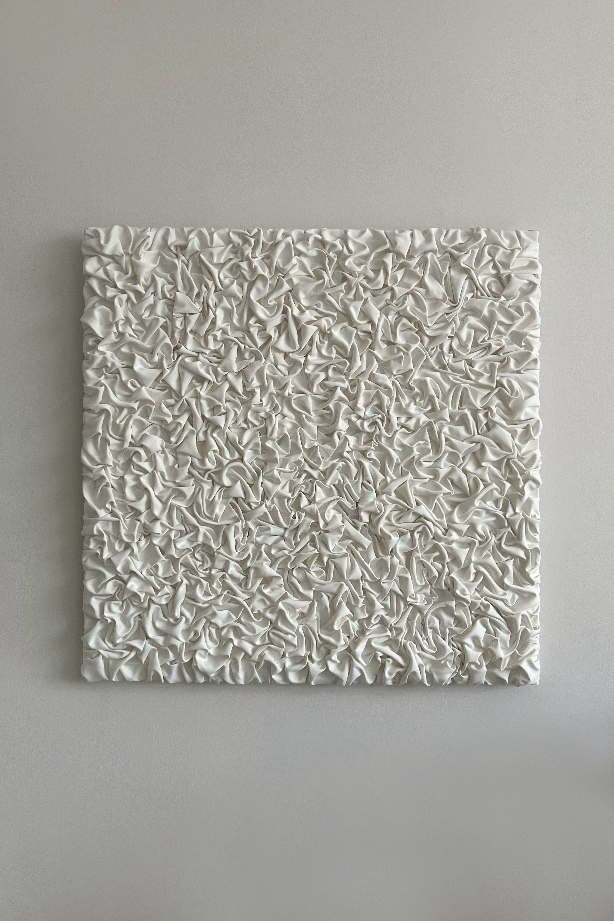 'ESCAPISM 108' Sculptural Wall Art by CARRARA Studio hangs on a gray wall, its square white form showcasing a textured, crumpled surface that evokes movement and depth—each original piece features unique variations.