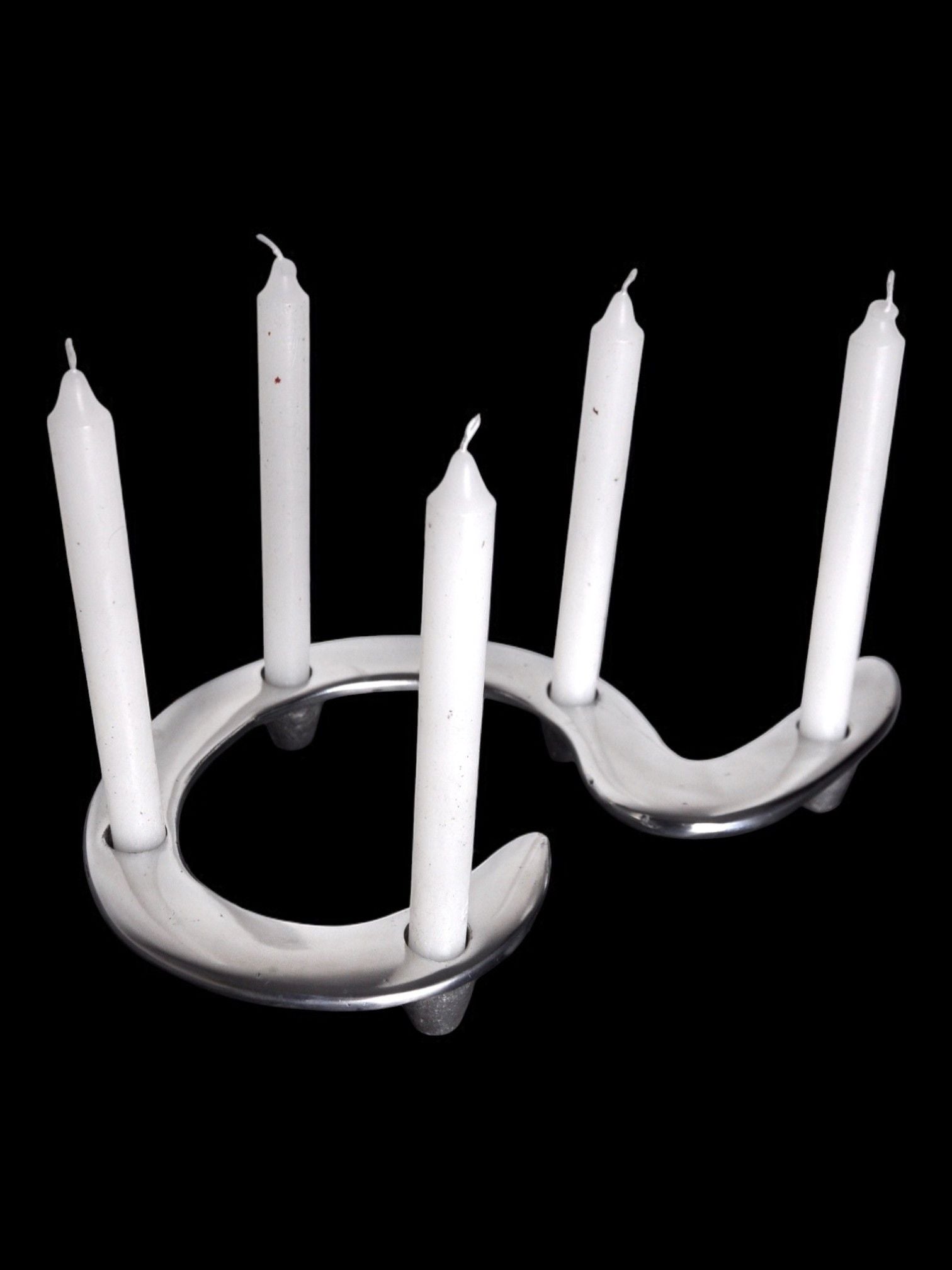 A modern Hook Candleholder England 1980 by Malamar Studio, crafted from solid aluminum, holds five white candles in a zigzag pattern. The sleek design against a black background echoes Brutalist style with the unlit candles.