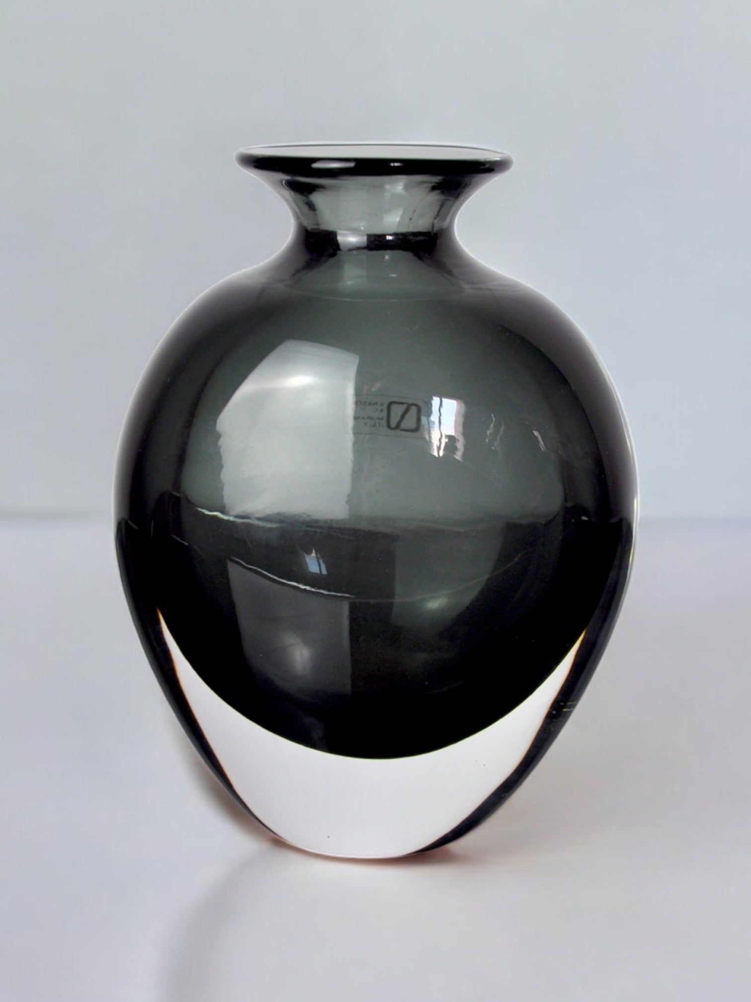 The Black vase by Vincenzo and Carlo Nason for Malamar Studio, Italy, 1960, features glossy Murano glass with a wide round body, narrow neck, and flared rim. Hand blown with sleek surfaces that reflect light against a plain background.