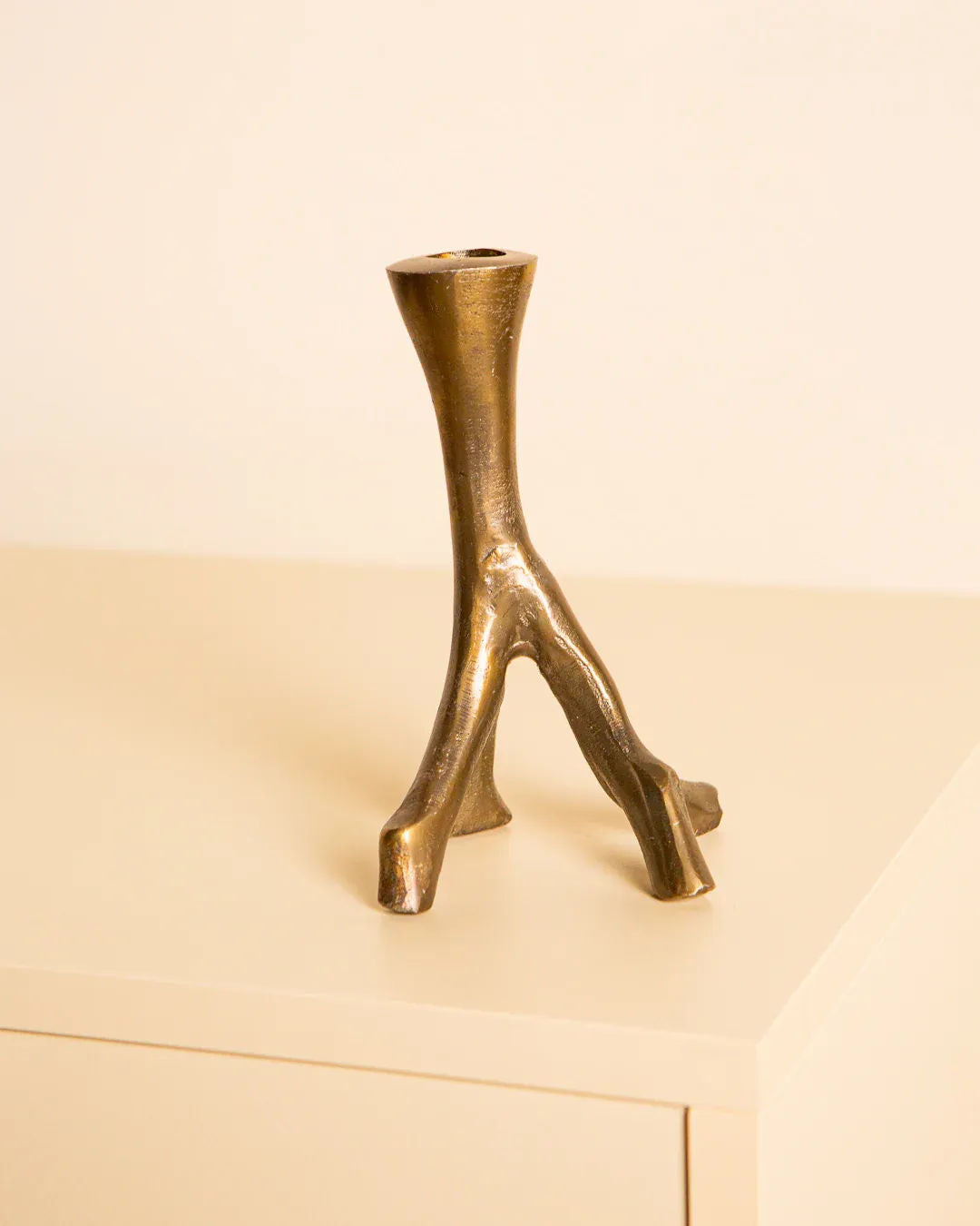 The 60's Brutalist "Arbre" candleholder by Treaptyque, featuring a unique bronze three-pronged base resembling branches, embodies an organic aesthetic and rests elegantly on a light-colored surface against a plain background, highlighting exquisite Italian craftsmanship.