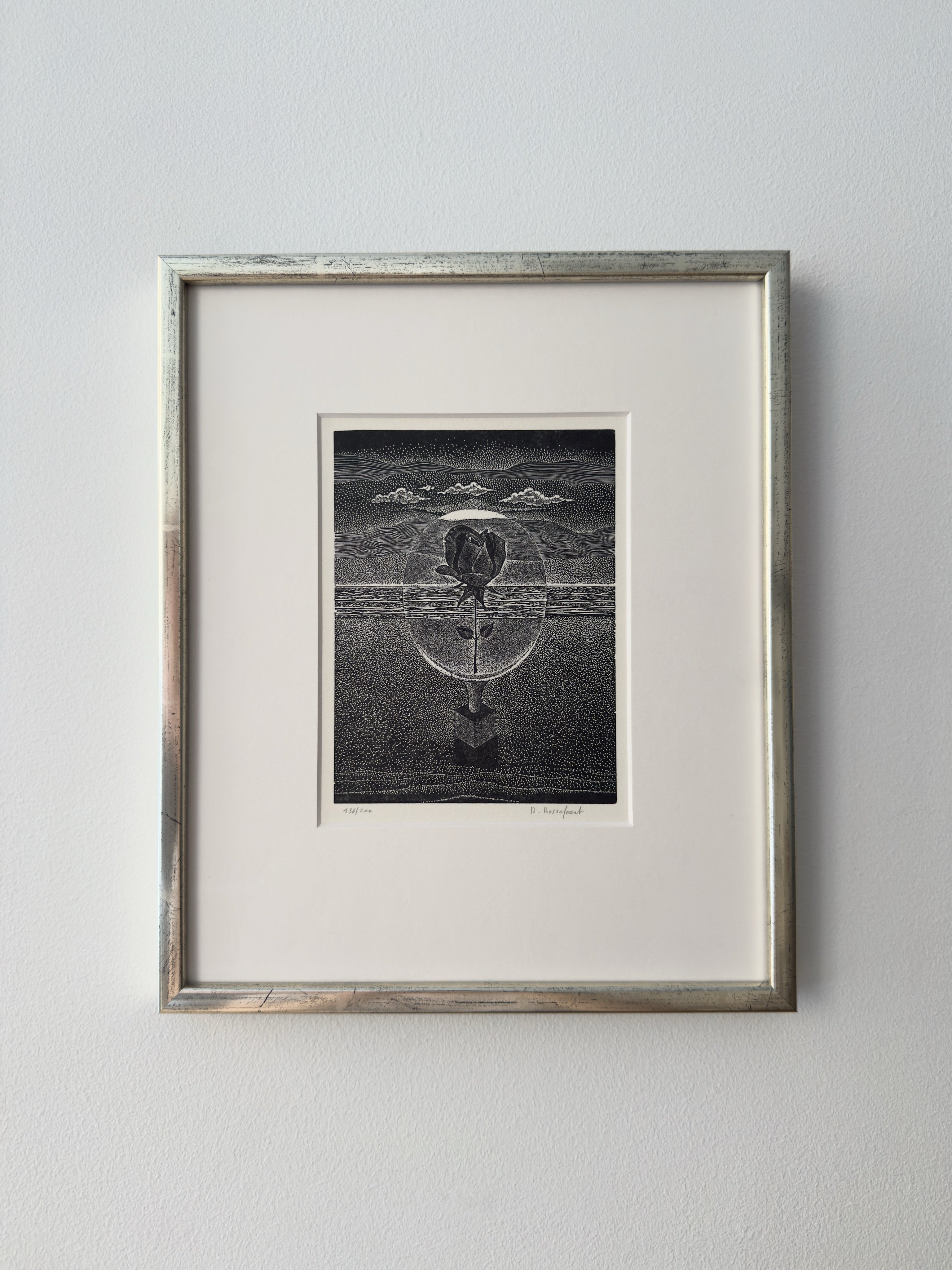 The "Surrealist Engraving by Renaat Bosschaert, I" from Galerie Storm features a rose in a transparent sphere against a textured scene, presented in striking black and white, and displayed framed on a white wall.