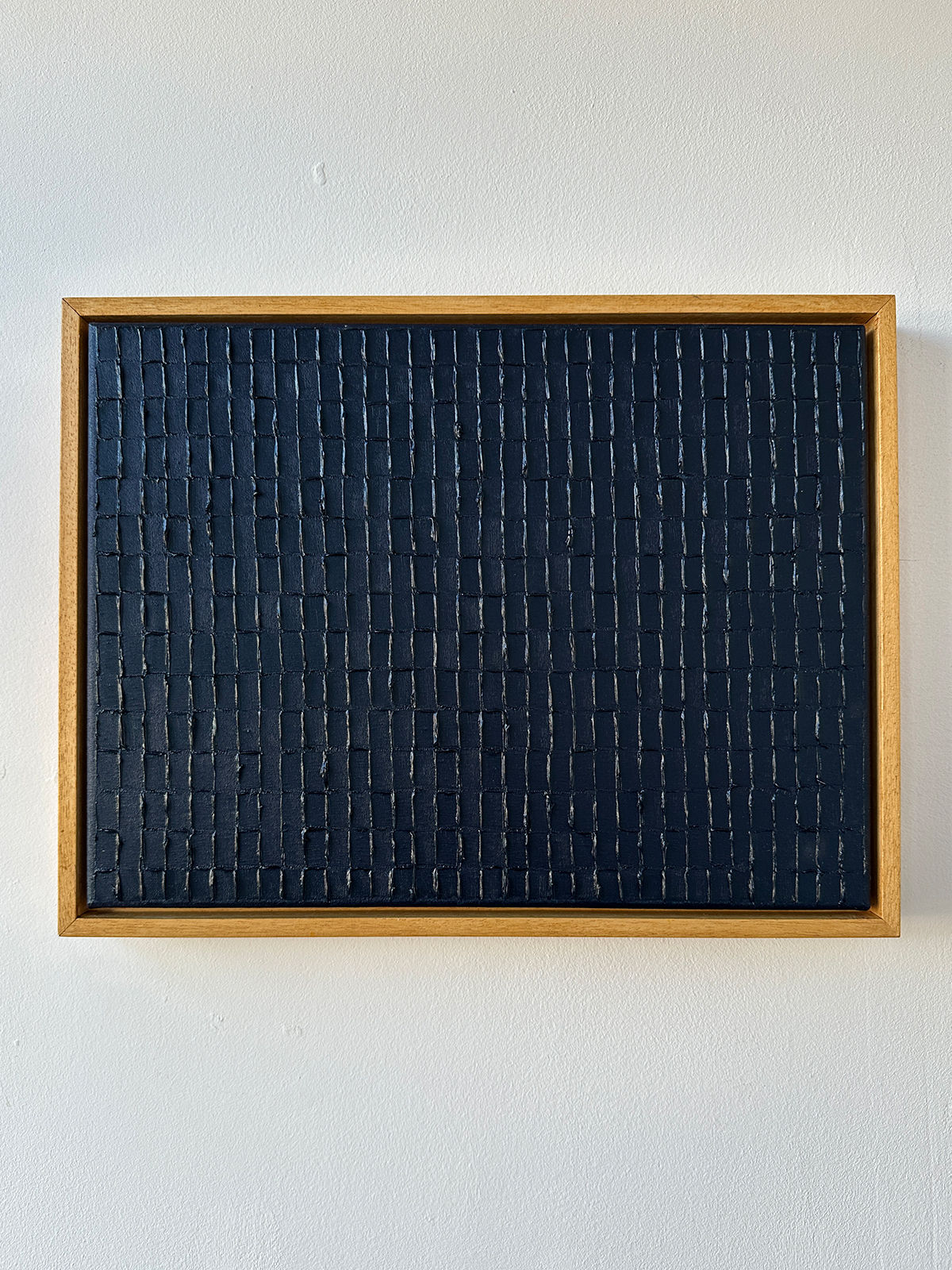 The "Prussian Blue - Oil on Canvas" by Roi Elmaliah is a rectangular art piece with a wooden frame, featuring a grid pattern on textured black. Precision-crafted thin lines form small raised rectangles throughout the artwork, and it's ready to ship.