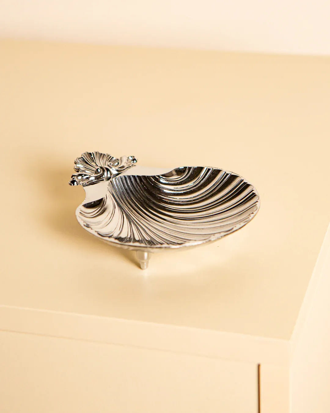 A small, silver Shell Shaped Italian Vide-poches from Treaptyque, crafted in the 80's with detailed shell accents, displayed on a light beige surface.