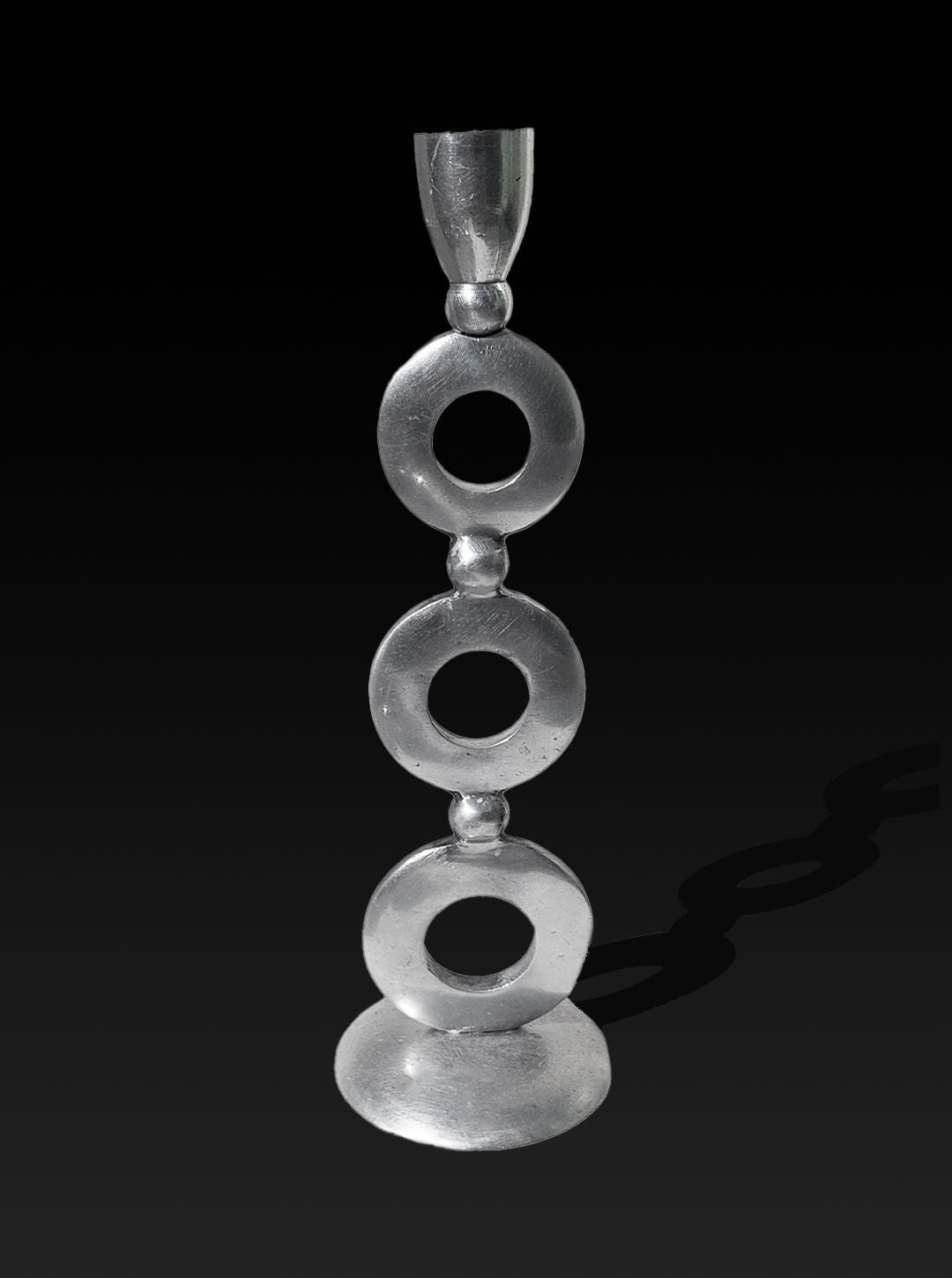 A sleek metal sculpture stands against a black background, showcasing a series of three stacked rings supported by small connecting spheres. The elegant silver plating and smooth, minimalist design add a modern, artistic flair, reminiscent of the vintage Totem Candle Holder by Les Objoies.