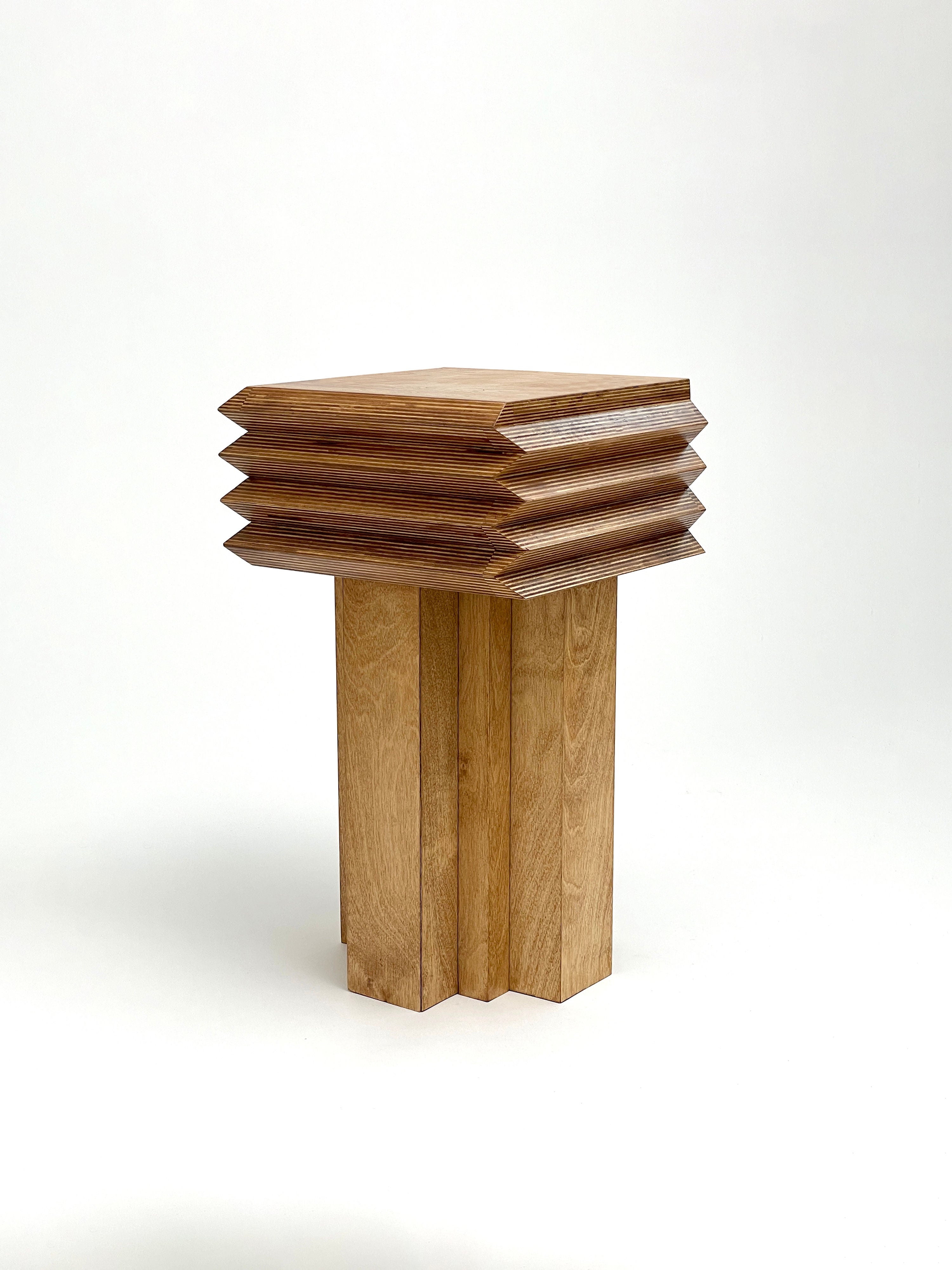 Introducing the MM Stool - Butterscotch by GOONS, a uniquely designed piece featuring a square top with layered sides that mimic stacked geometric shapes. This handcrafted stool stands on a multi-faceted base, exemplifying artisanal craftsmanship using light brown wood.