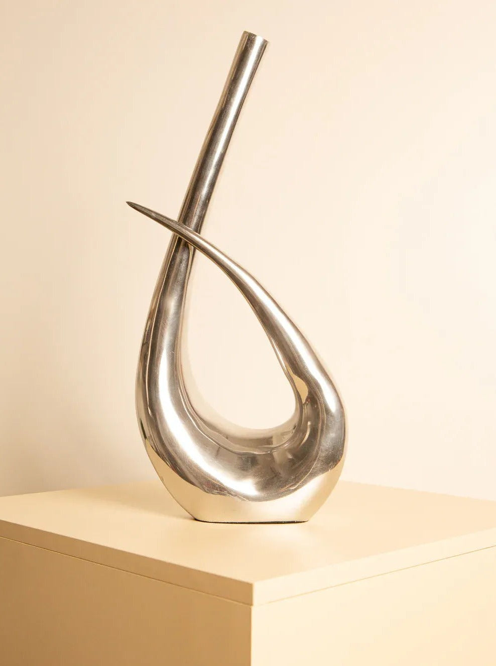 Large Metal Clef Vase 80's in shiny silver finish, standing on a wooden table, with flowers and greenery inside