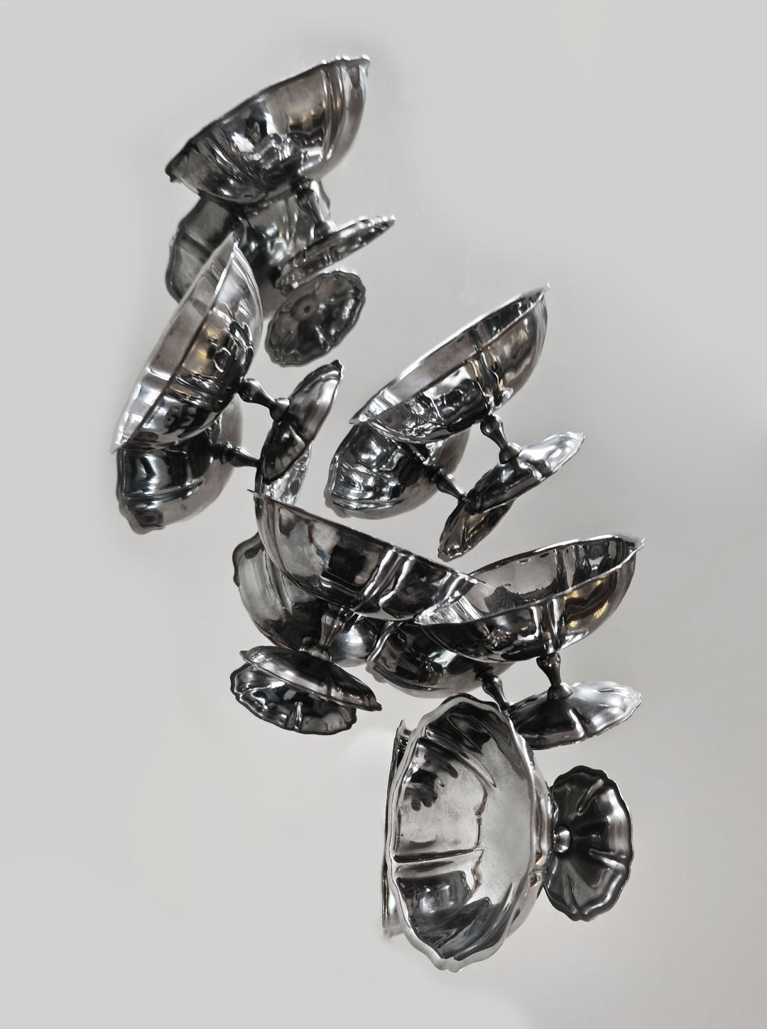 Les Objoies' Set of 6 Dessert Cups features a sculptural arrangement of interconnected stainless steel cups and discs with reflective surfaces, appearing to float vertically against a neutral backdrop for an intriguing visual display.