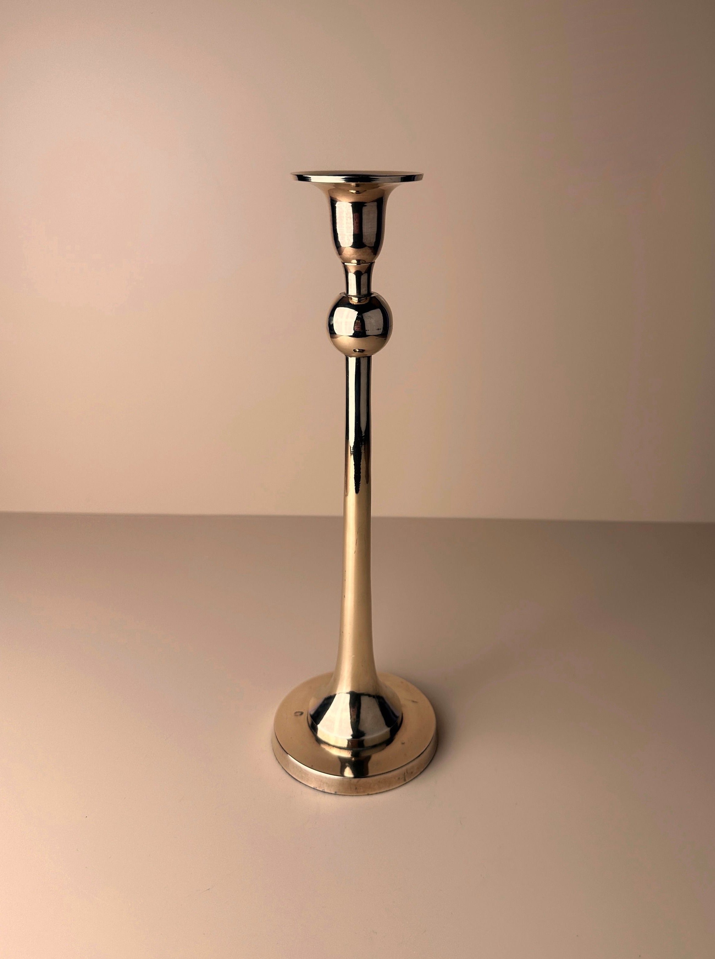 A sleek, silver-colored Postmodern Brass Candleholder from Dodo Vintage with a round base and a slender, tapered stem is centered against a neutral background. The holder, reminiscent of Memphis style design, has a polished, reflective surface and a narrow cup at the top for holding a candle.