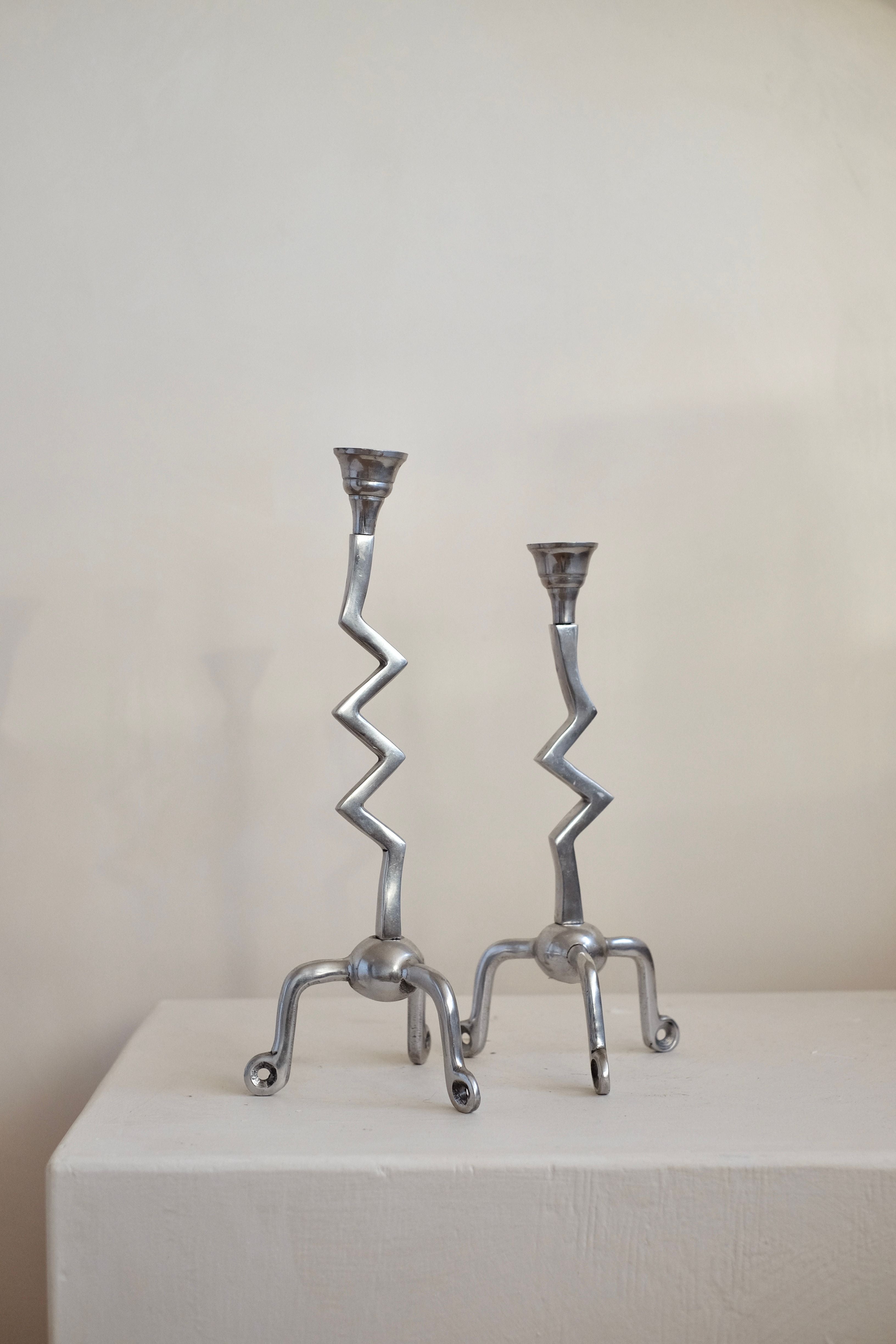 A pair from the Set of Zigzag Candleholders by septembre studios is displayed on a white surface against a simple, light backdrop. Their rare design features zigzag stems and claw-like bases, offering an abstract and artistic look reminiscent of vintage zilver craftsmanship.