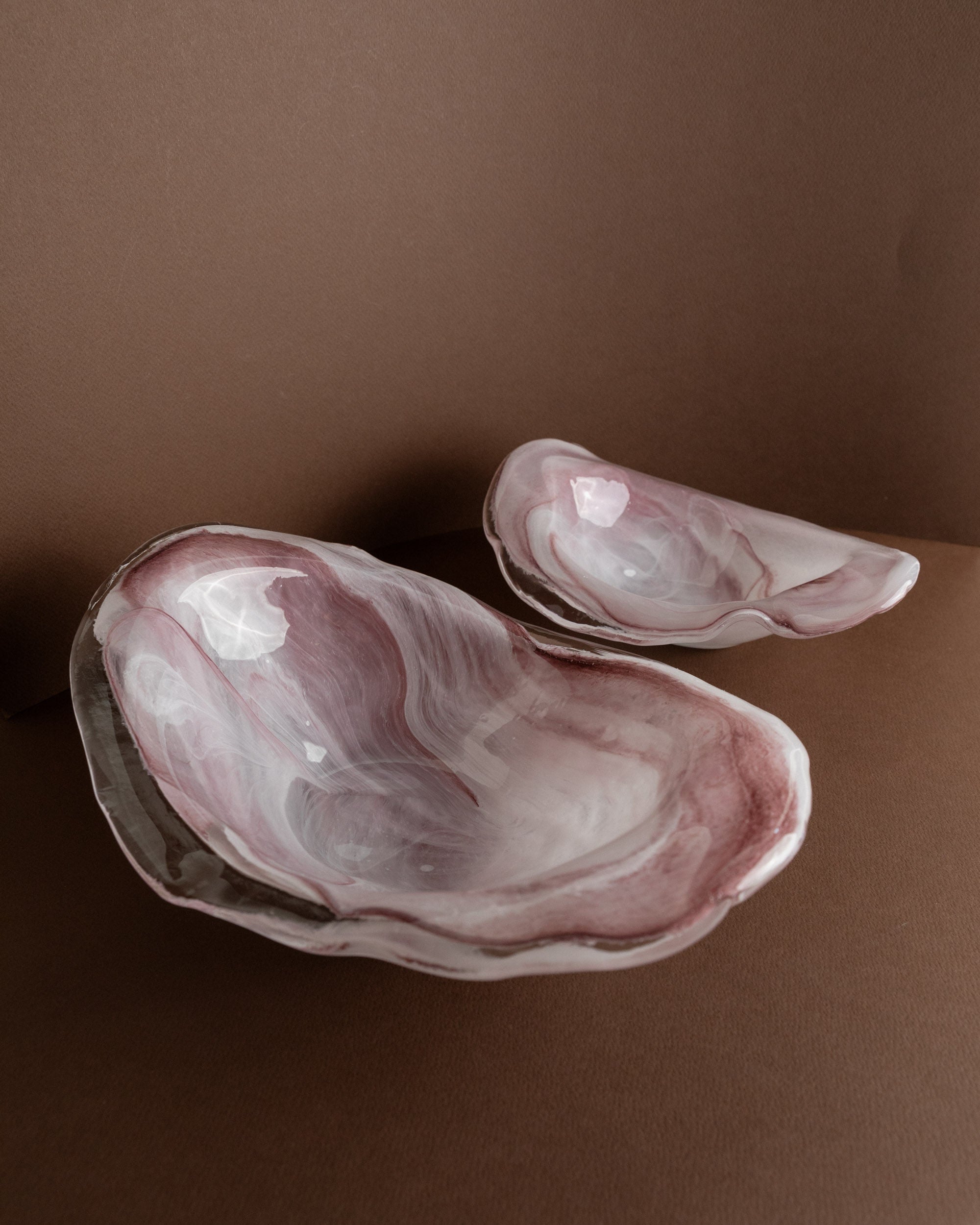 Two Murano Glass Bowls by Bottega Jacobs, Italy 1970s, feature irregular organic shapes and marbled pink and white hues, evoking vintage charm as they rest on a brown surface with a matching background.