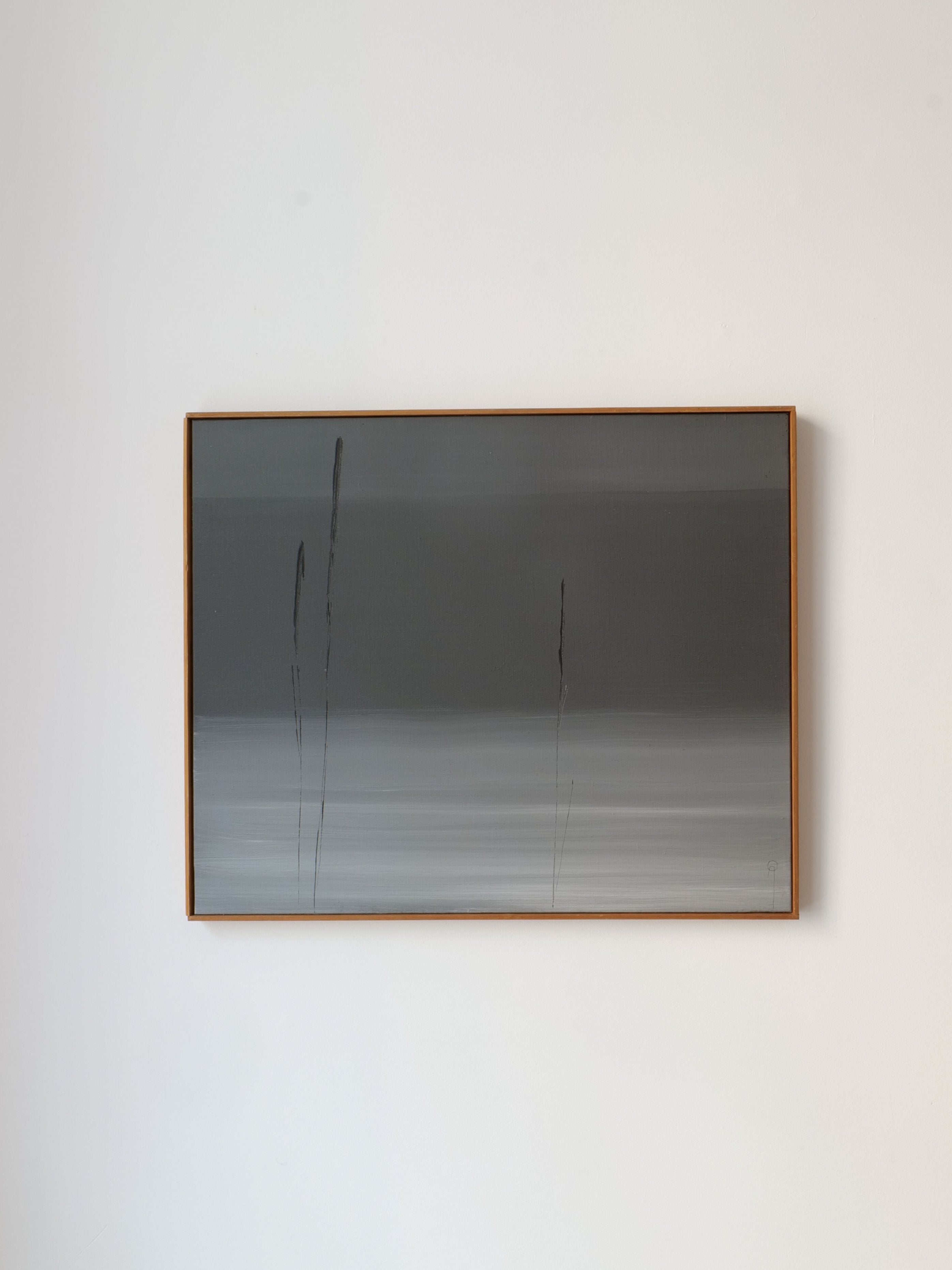 A framed "Strandlinje Arne Olsson" painting by Collection apart hangs on a plain white wall. The artwork, reminiscent of a Scandinavian shoreline, features a gradient of dark to light gray tones with a few thin, vertical black lines extending from the bottom toward the top.