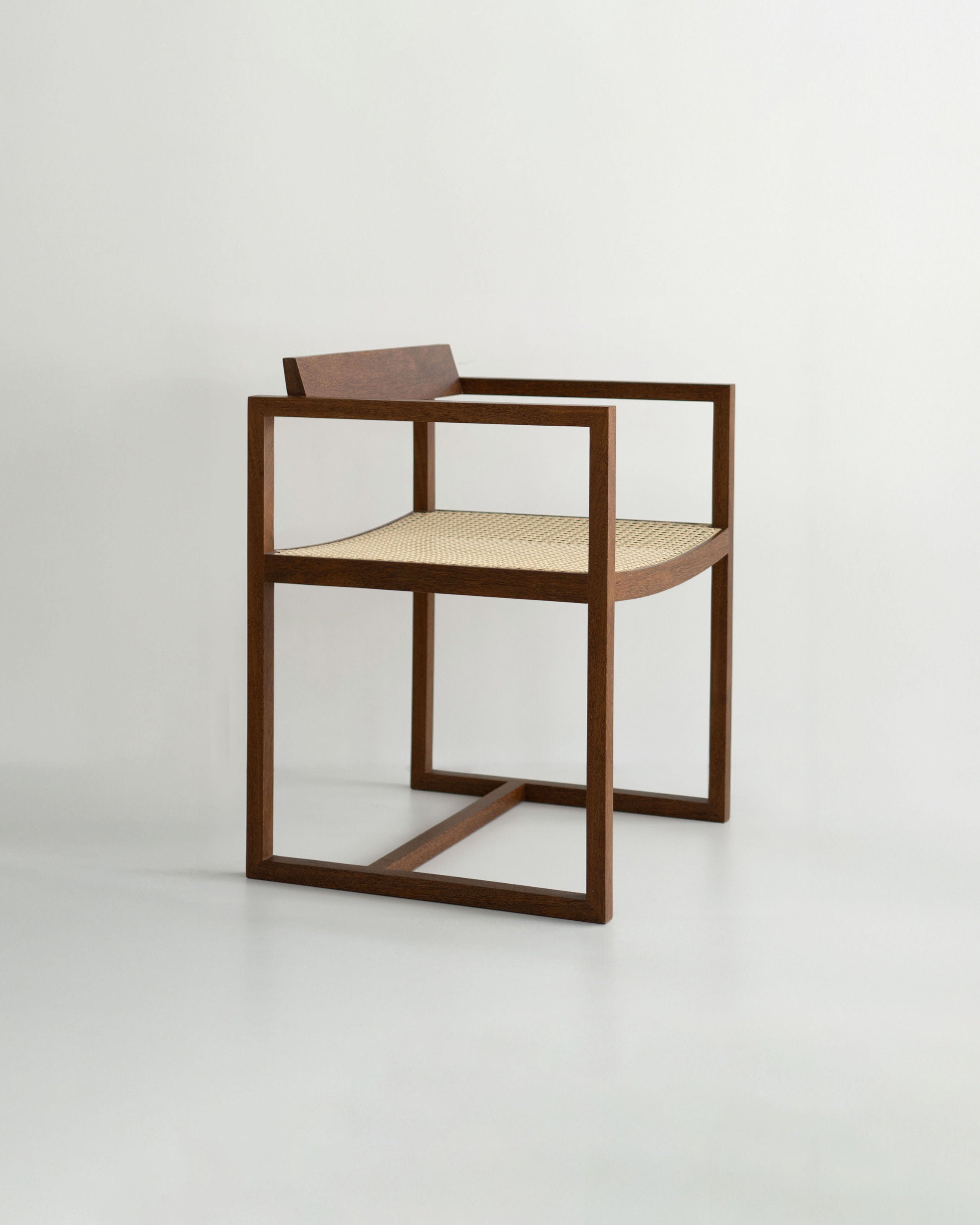 The "Amélia" Armchair by Andre Grippi features a minimalist wooden square frame, straight armrests, and a woven straw seat, displayed against a plain light background.