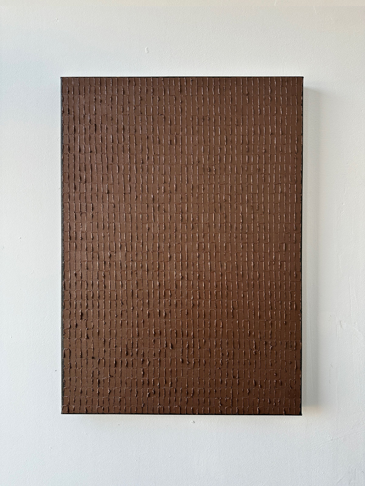 'Light Umber' by Roi Elmaliah is a rectangular oil on canvas featuring a uniform brown color with vertical, textured lines forming a subtle grid. Reminiscent of Dutch art, it’s displayed against a plain white wall.
