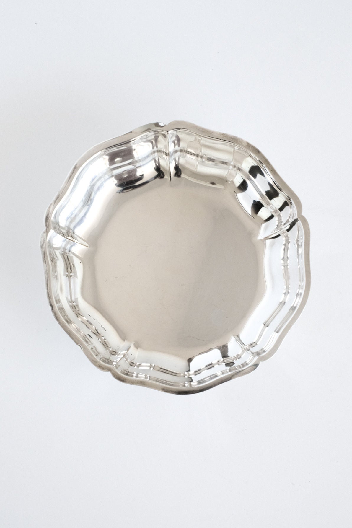 The Silver-plated Bowl by septembre studios features a shiny, round design with a scalloped edge, shown from above on a plain white background.