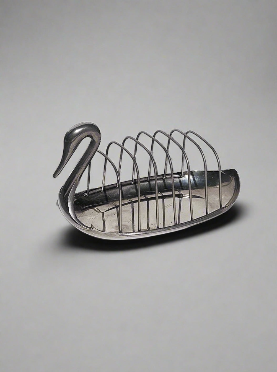 A decorative brass Les Objoies swan-shaped toast rack with six slots, designed to hold slices of bread, depicted against a white background.