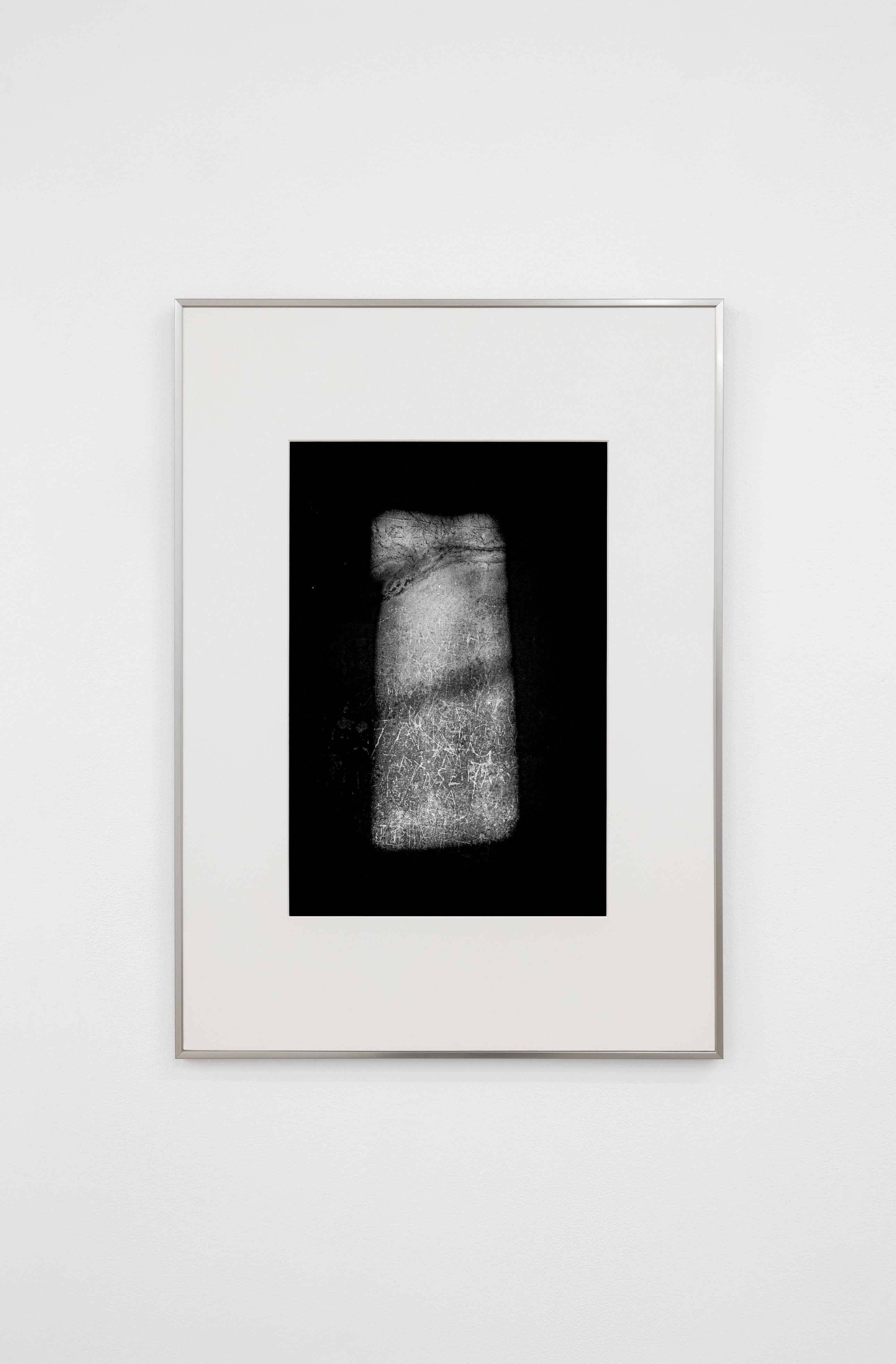 A limited edition framed 'Memory #12 - Pompei' black-and-white abstract print by COSEINCORSO hangs on a white wall, showing a rectangular, textured light gray shape centered against a black background.