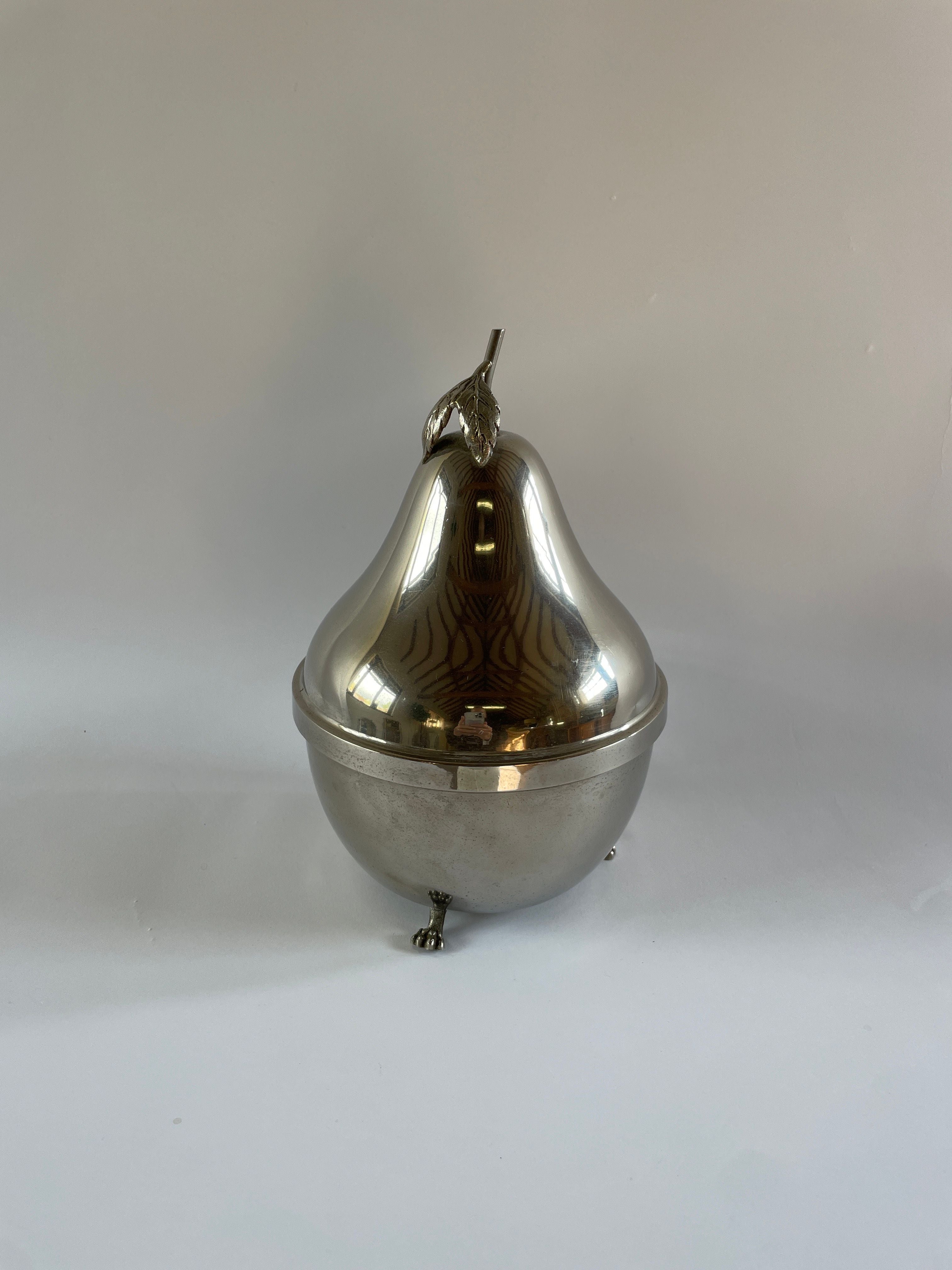 A glossy, chrome-plated Mid-century French Pear Carafe by Maud Vaughan, complete with a lid and a slender stem on top. This exquisite carafe, resting on tiny feet against a simple background, exudes elegance whether used for pouring or display.