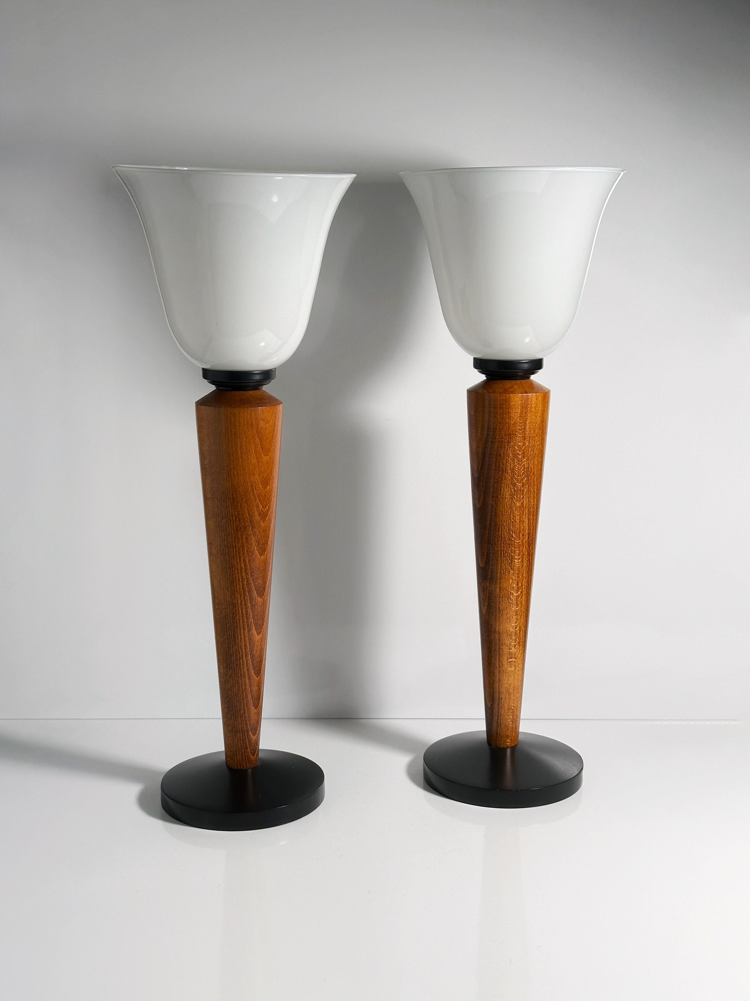 The Dodo Vintage Pair of Art Deco Chalices with Teak Wood features frosted glass shades and tapered teak bases on round black platforms, displayed side by side against a plain white background.