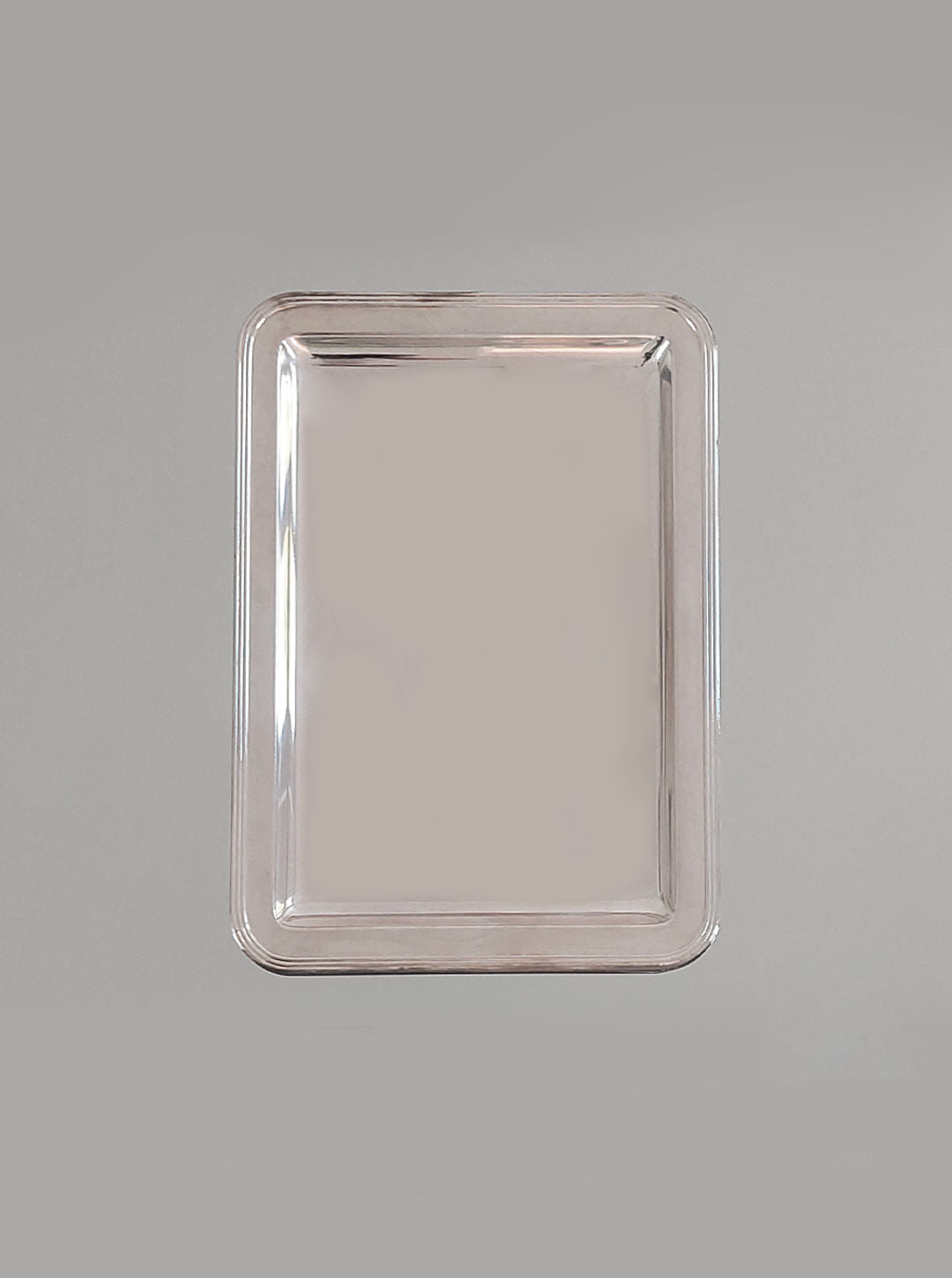Displayed against a plain gray background, the Les Objoies Silver-plated Rectangle Tray features raised edges and a smooth, reflective surface. This minimalist tray embodies a modern aesthetic and appears empty.