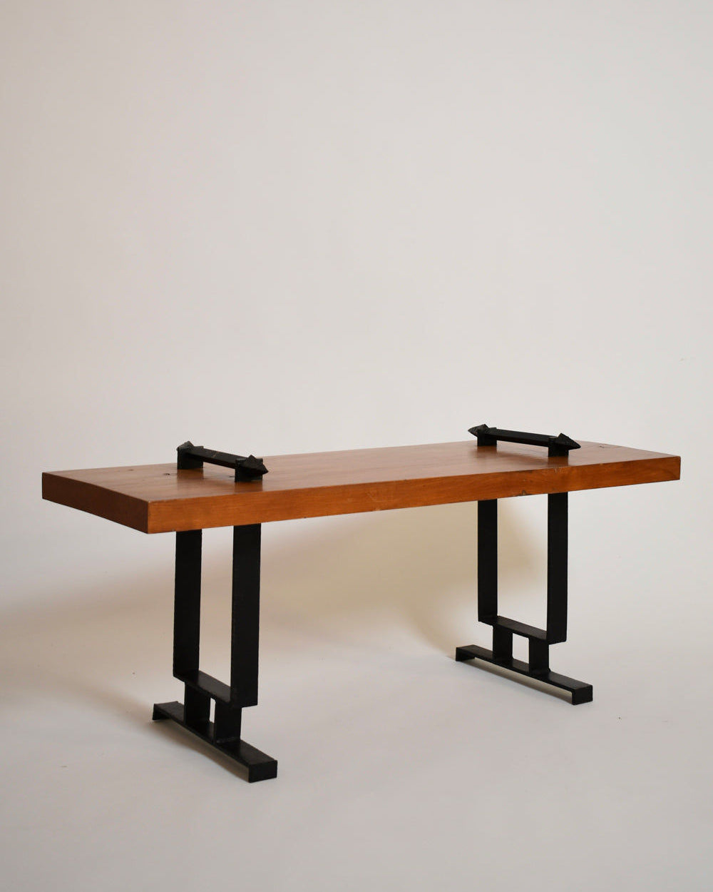 The Barracuda Interiors Wrought Iron and Natural Wood Coffee Table, 1950s, features a thick rectangular wood top with two geometric black iron legs and small black handles on each end.