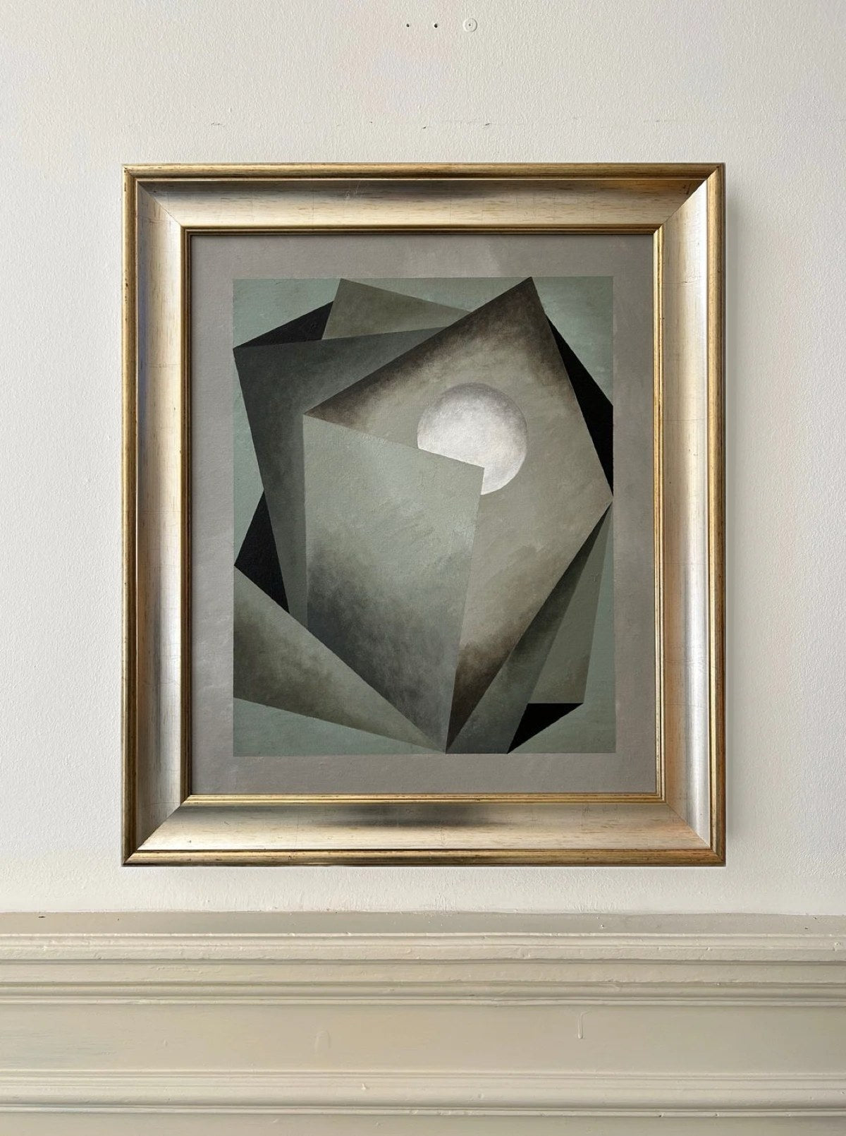 The "Nest" painting by Iris Bavelaar features overlapping geometric shapes in muted gray and forest green, accented by a white circle. Set in a gold frame with a gray mat, this sophisticated linen wall art adds a contemporary touch to any space.