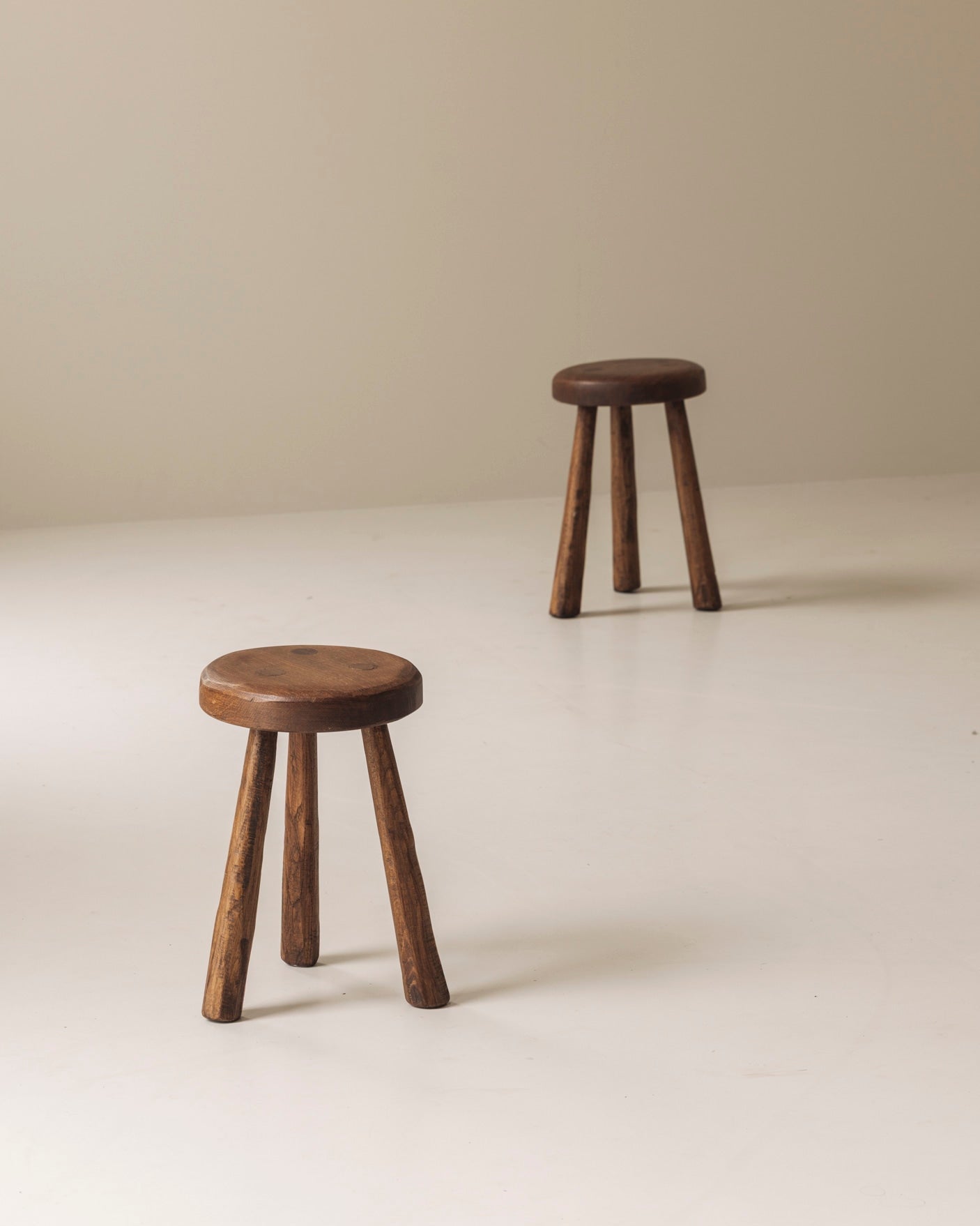 Set of two solid elm tripod stools from France, 1950s — side angle