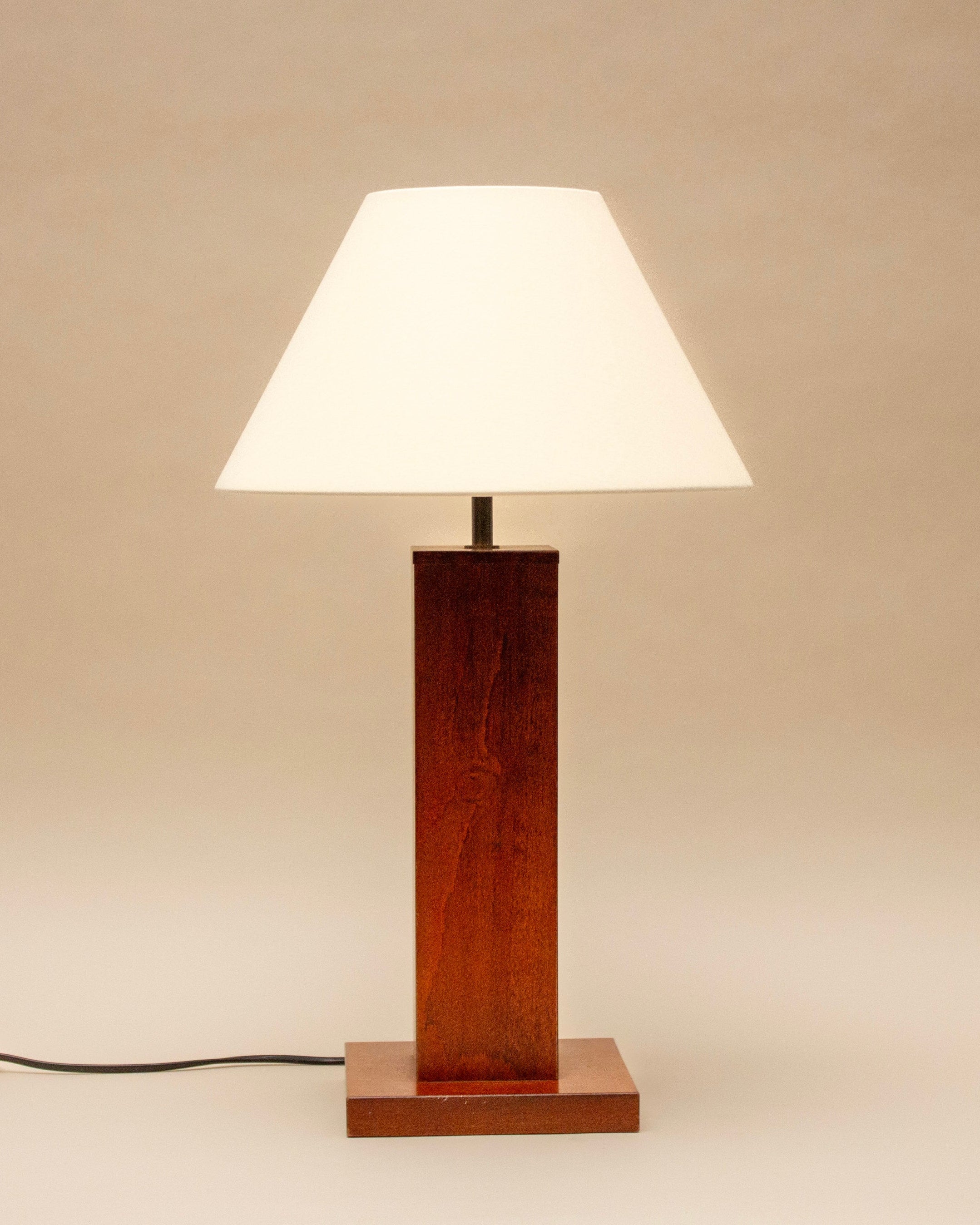 The SÒLER Almeria Table Lamp, with a vintage wooden rectangular base, cream shade, and visible black power cord, stands on a neutral background.