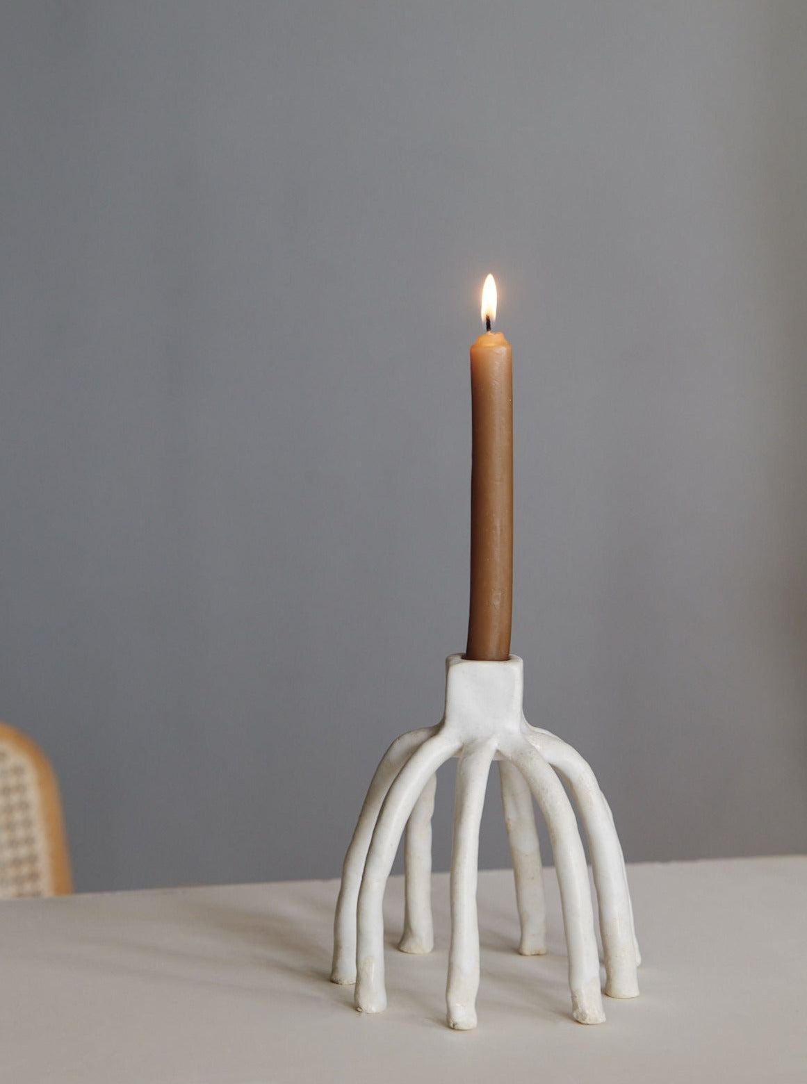 White ceramic arch candleholder with lit beeswax candle by Claire Pain