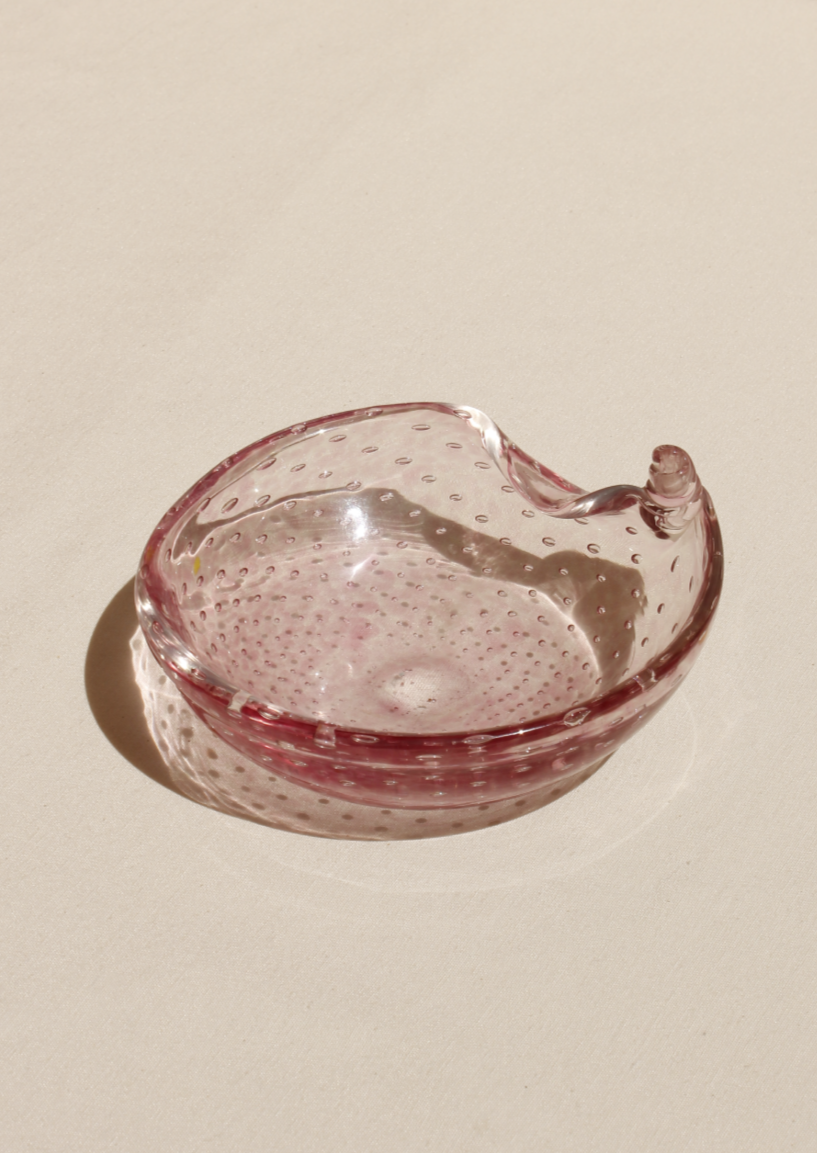 Pink Bullicante Murano Bowl shaped like a curled-up leaf, featuring raised bubbles and a stem, placed on a beige surface with soft shadows. Brand: Boga Avante Shop.