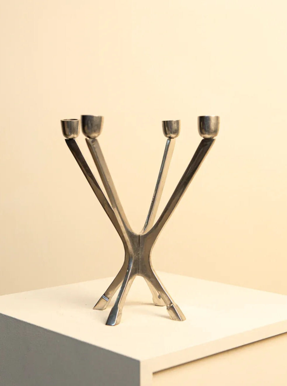 A vintage Treaptyque Candelabra in 70's Metal with a split x-shaped base and four upward-facing candle receptacles, displayed against a soft beige background.