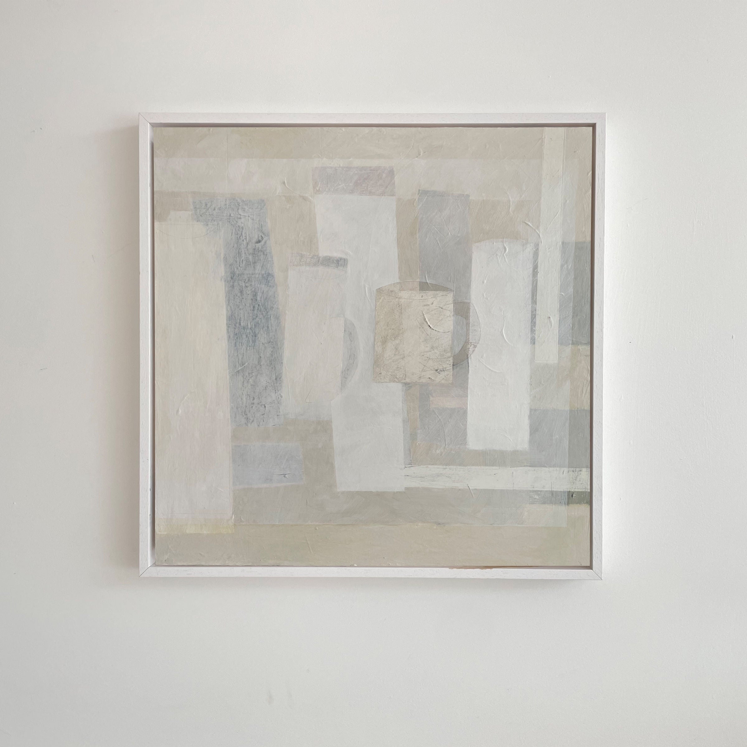 The "Every Shade Of Pale" framed abstract painting by Lara Voce features sculptural rectangles in muted gray, white, and beige. Its overlapping geometric forms enhance depth and subtle texture, adding elegance to a minimalist interior against a plain white wall—ideal for a luxury aesthetic.