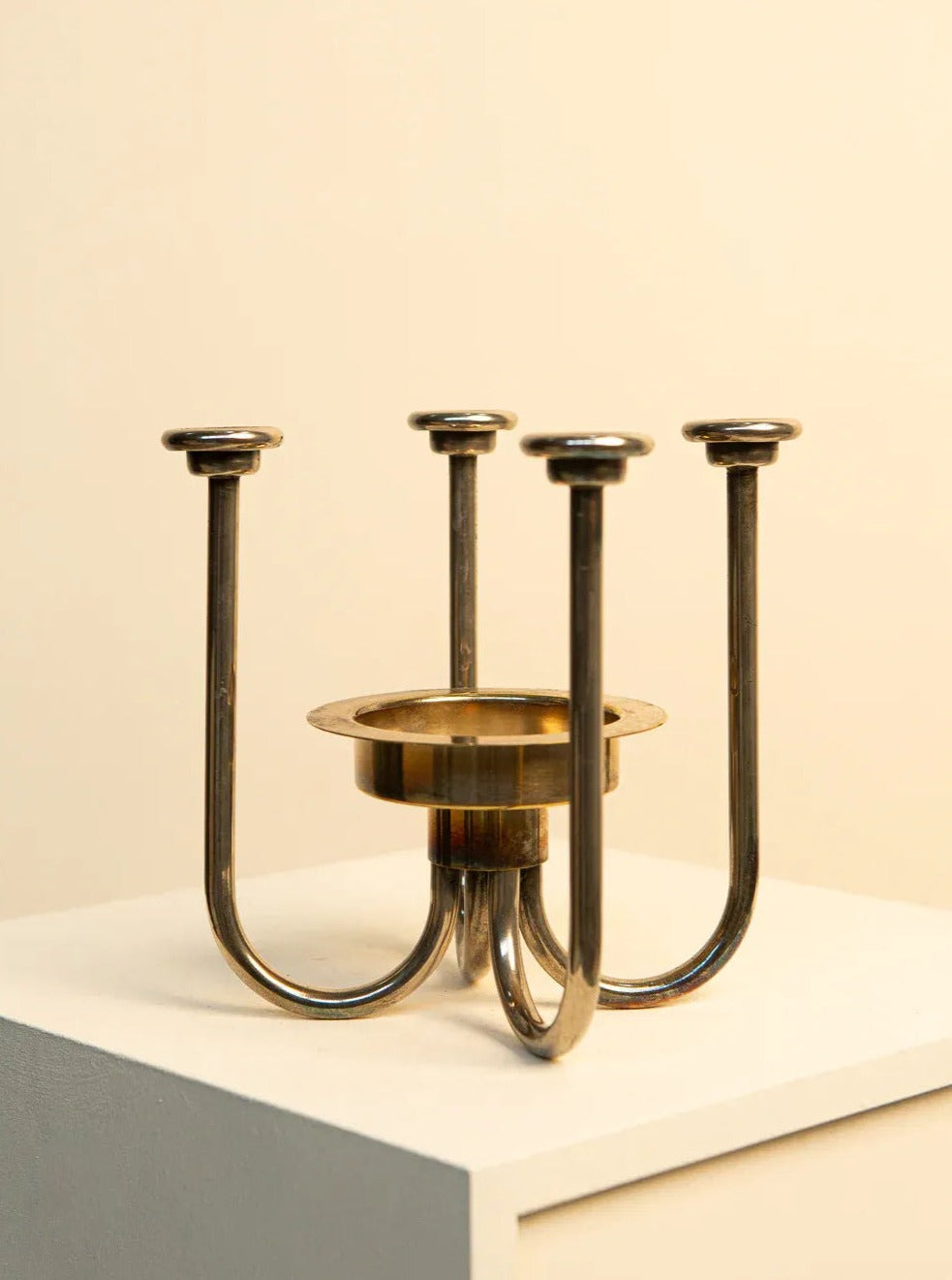 Vintage Treaptyque bronze candle holder with three curved arms, each ending in a flat disk designed to hold candles, displayed against a beige background.