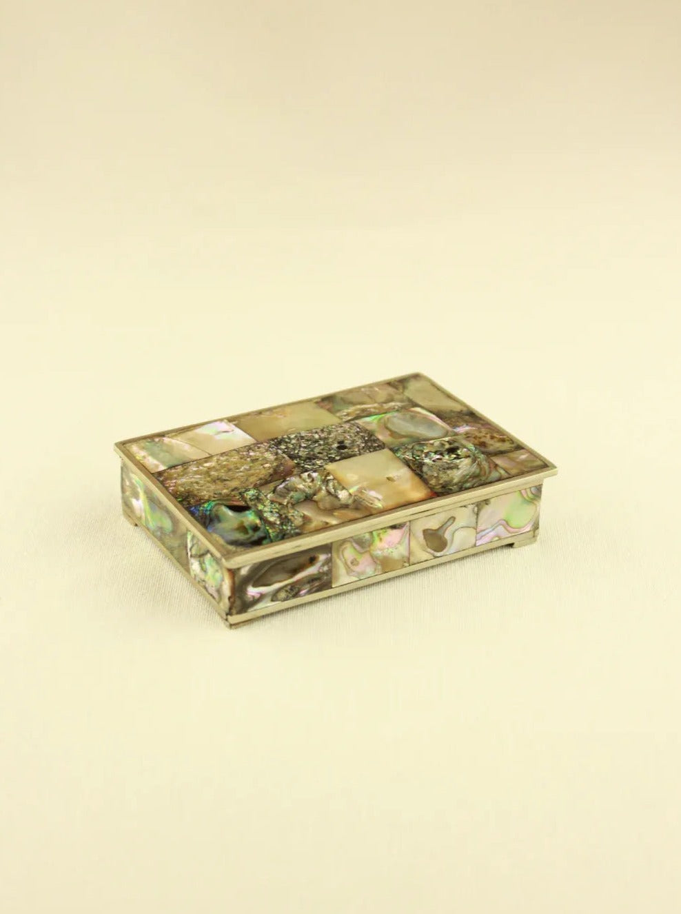 An antique rectangular jewelry box with mother-of-pearl inlay and intricate silver-plated alpaca detailing, displayed against a neutral background.