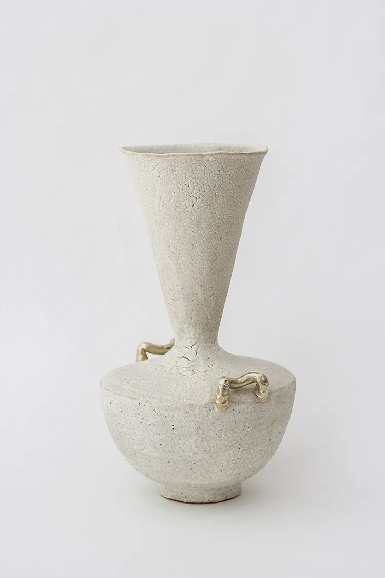 The Isolated n.15 Vase by Canoa Lab is a beige ceramic piece with a sculptural design, featuring a wide, funnel-shaped top that narrows at the waist and expands into a round base. It has two small golden handles on each side, embodying contemporary design against a plain white background.