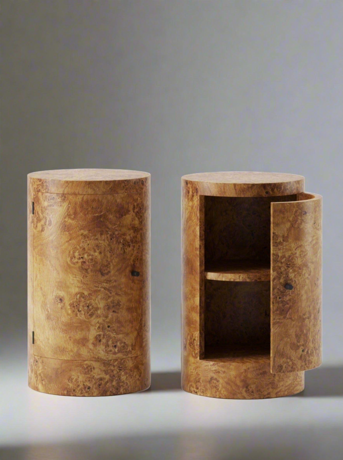 Two cylindrical wooden Constant Nightstands in Poplar Burl with meticulous craftsmanship, one closed and the other open with shelving inside, against a plain white background. (Brand: Lemon)