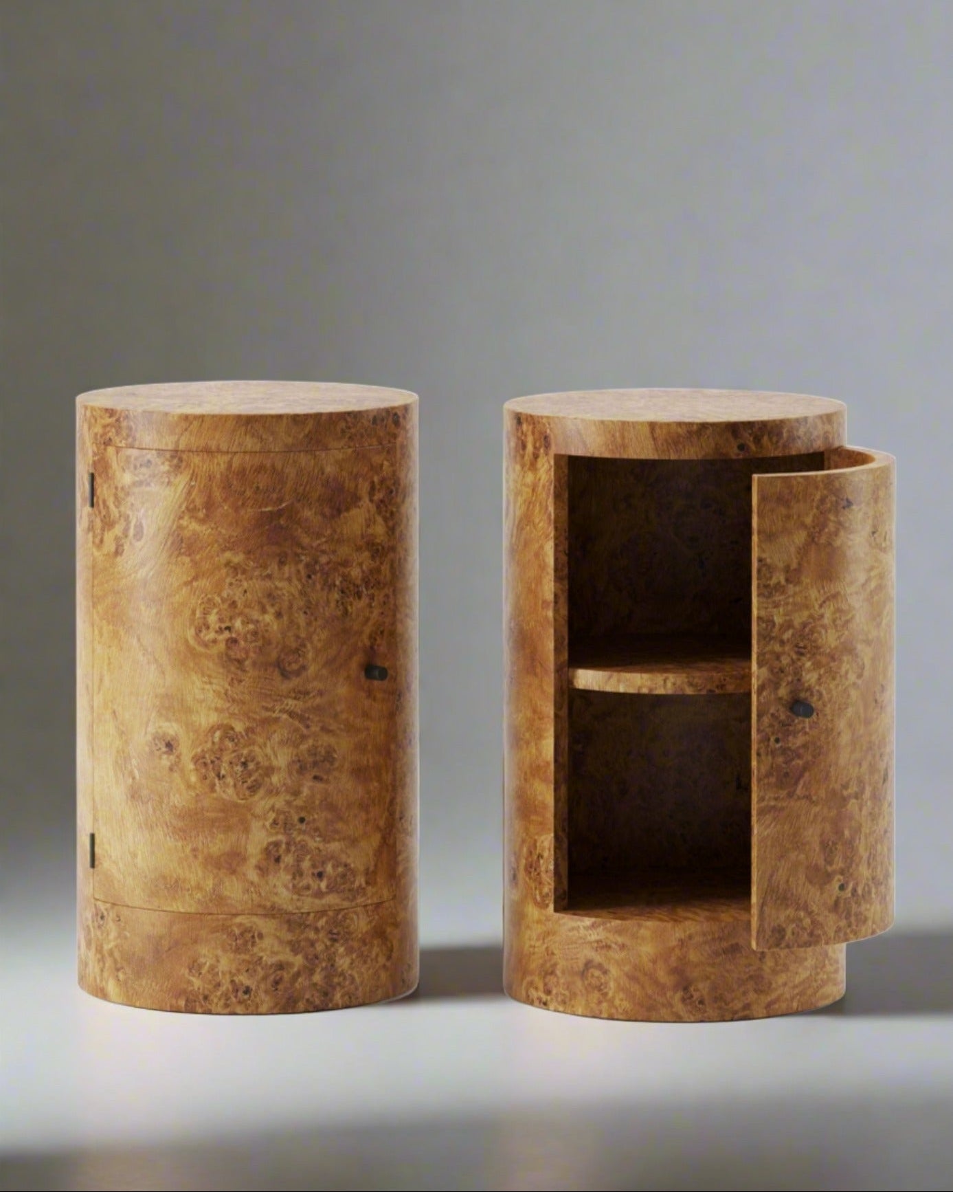 Two cylindrical wooden Constant Nightstands in Poplar Burl with meticulous craftsmanship, one closed and the other open with shelving inside, against a plain white background. (Brand: Lemon)