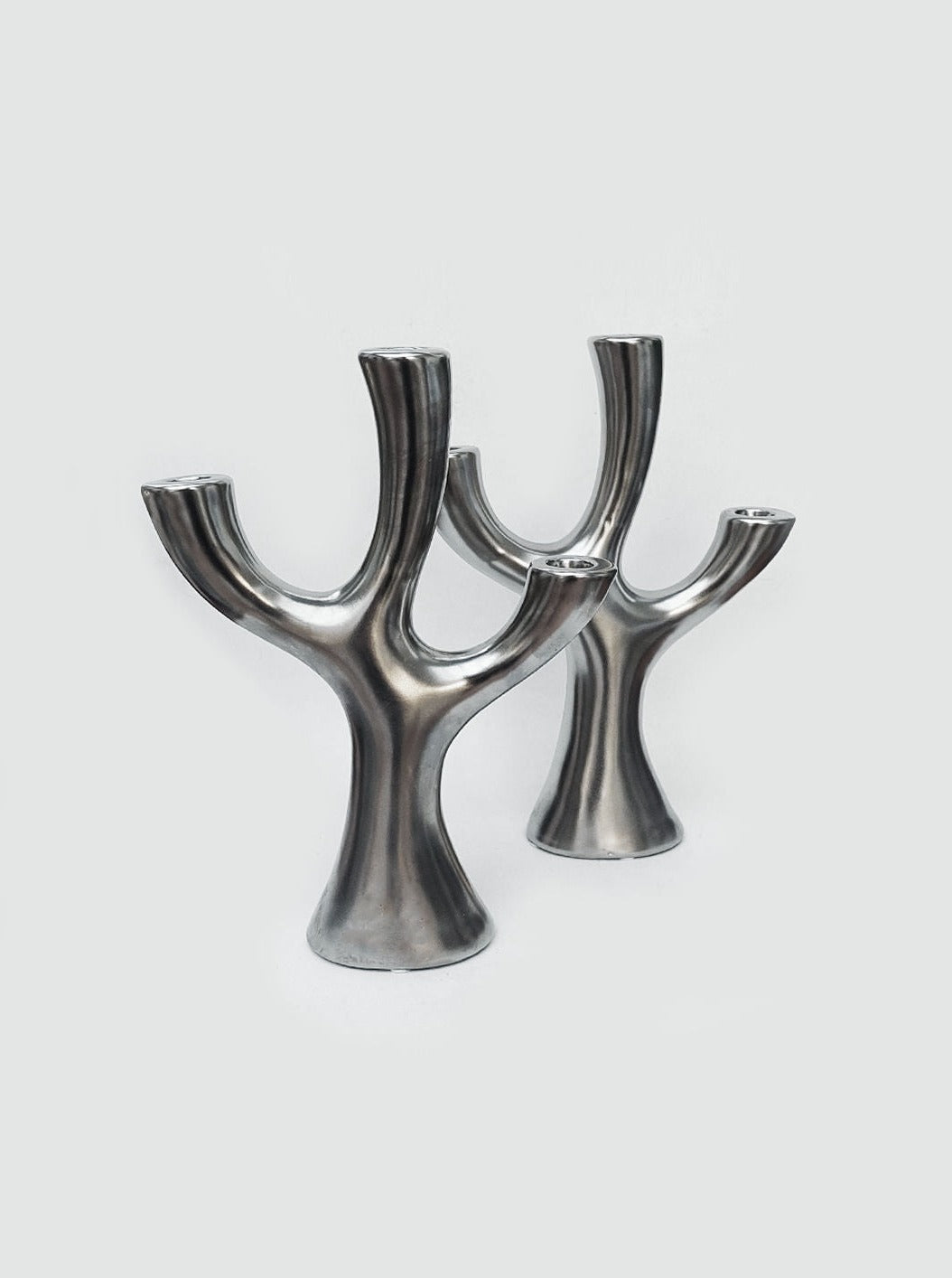 A pair of black metal tree-shaped candle holders with intricate details