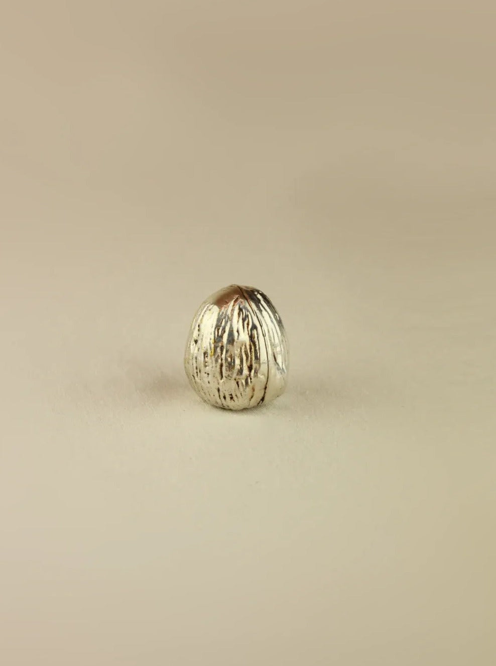 Handcrafted silver walnut sculpture with intricate carved details and polished finish