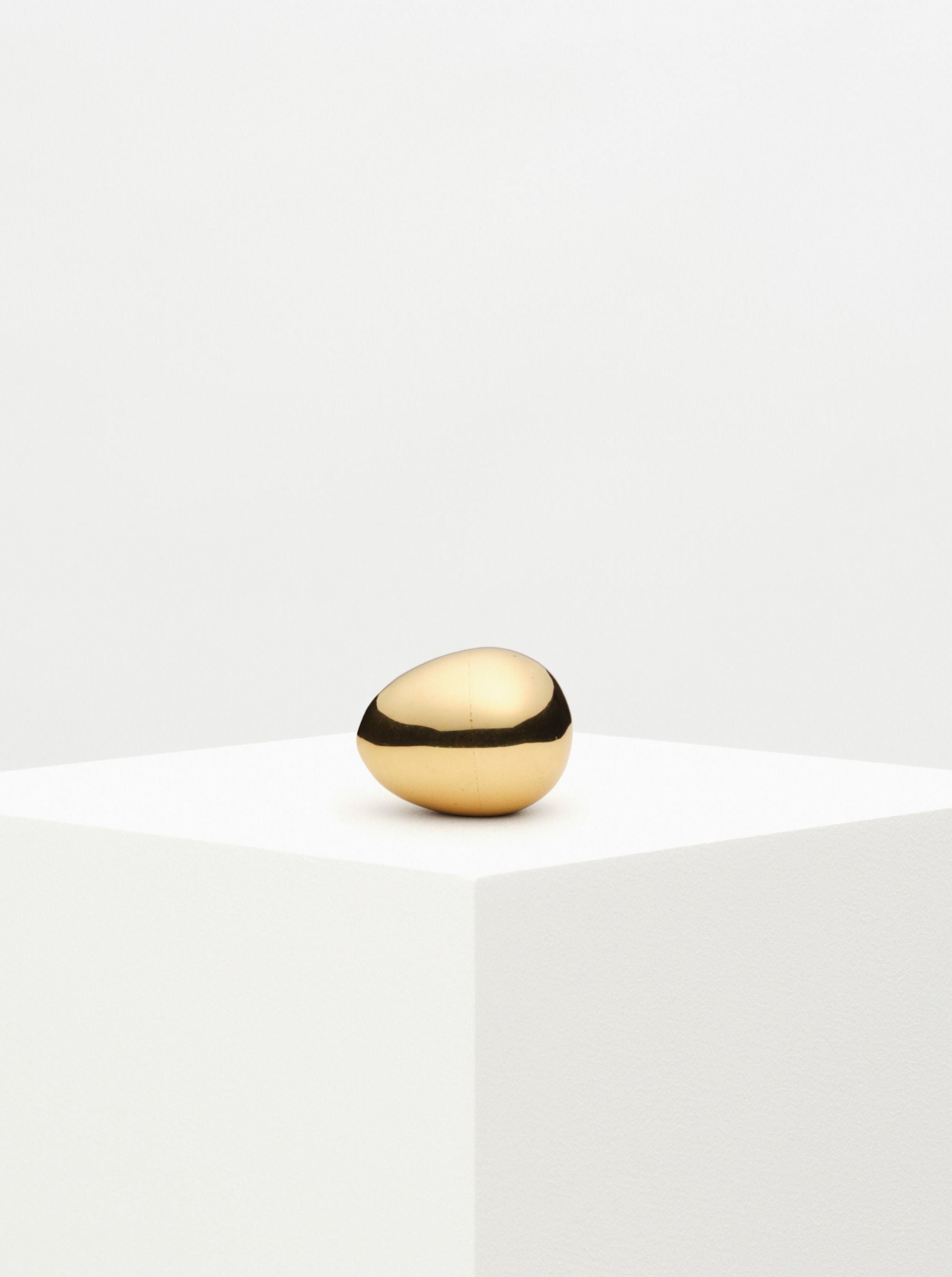 Brass egg-shaped paperweight with intricate engraved floral design